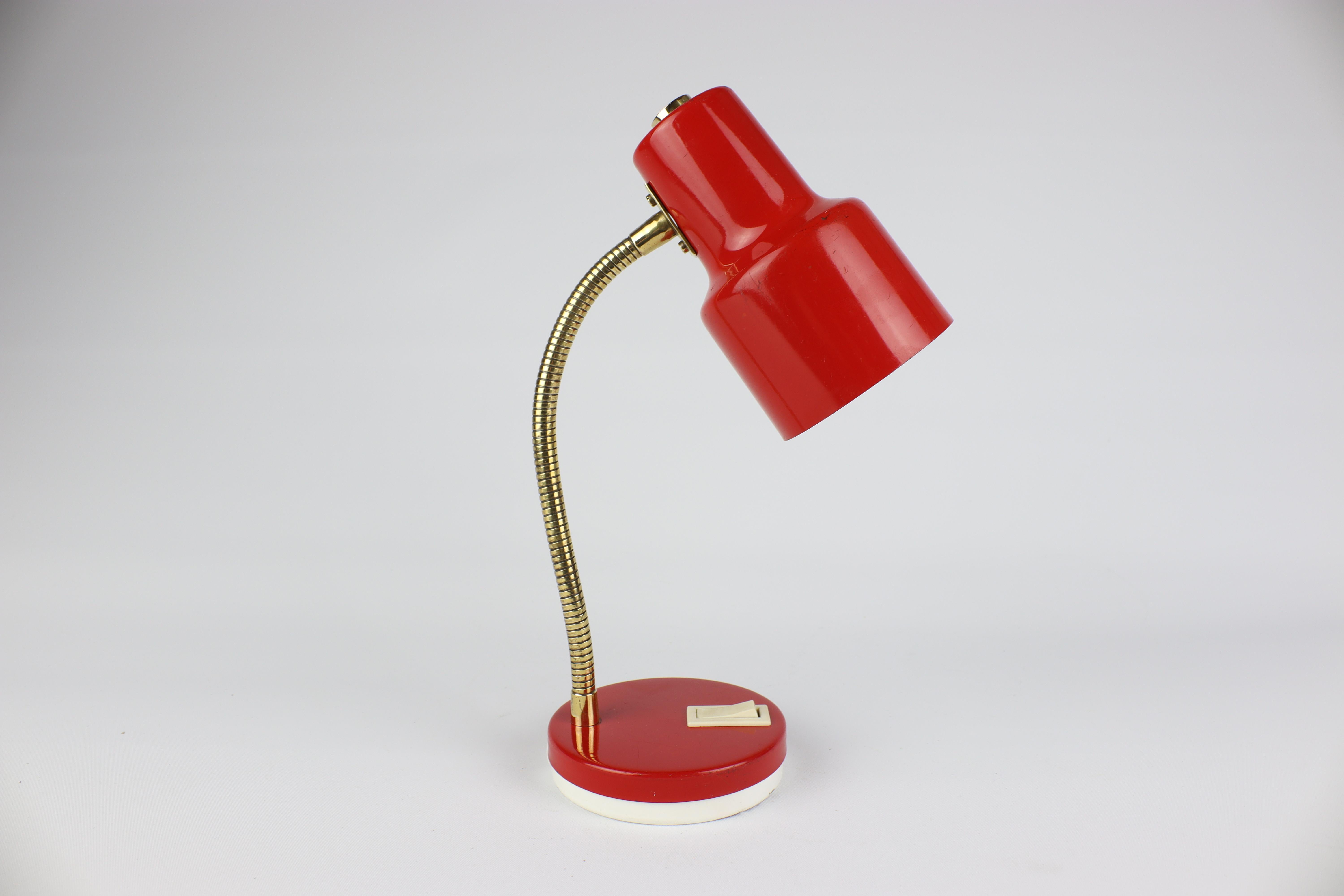 You will fall in love with this lamp thanks to its elegant all-metal design, which is dominated by red. The luminaire is complemented by a brass foot in the form of a gooseneck, which harmonizes with the overall design and allows the lamp to be