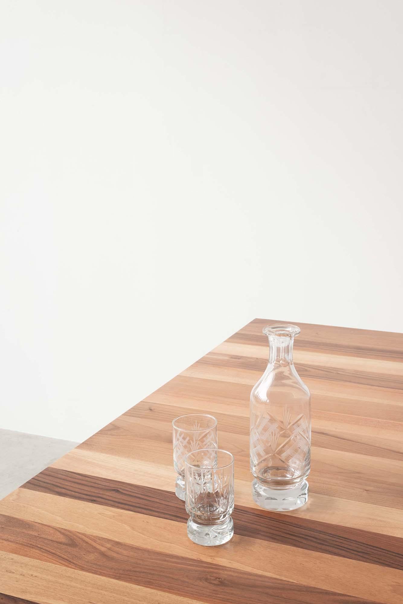 Vier dünne lackierte Metallbeine tragen eine massive Platte aus europäischem Nussbaum.
Eine quadratische Form der Tisch hält ein einfaches Design mit einer naiven und strengen Linie.

Designer: Roberto Cicchinè.
 