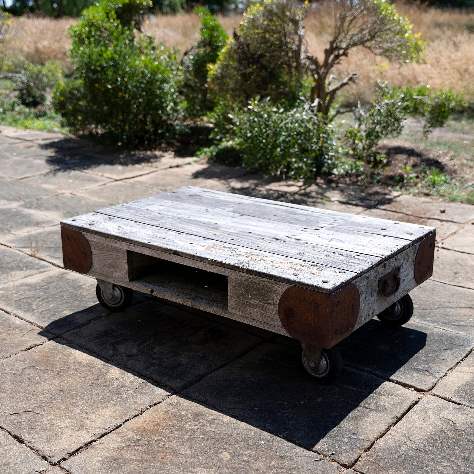 An unusual and characterful teak table with a recess for storage on lockable castors suitable for outside use in the garden, patio, conservatory. Weathered to a beautiful silver grey wit traces of old paint and paper on the top and durable. The