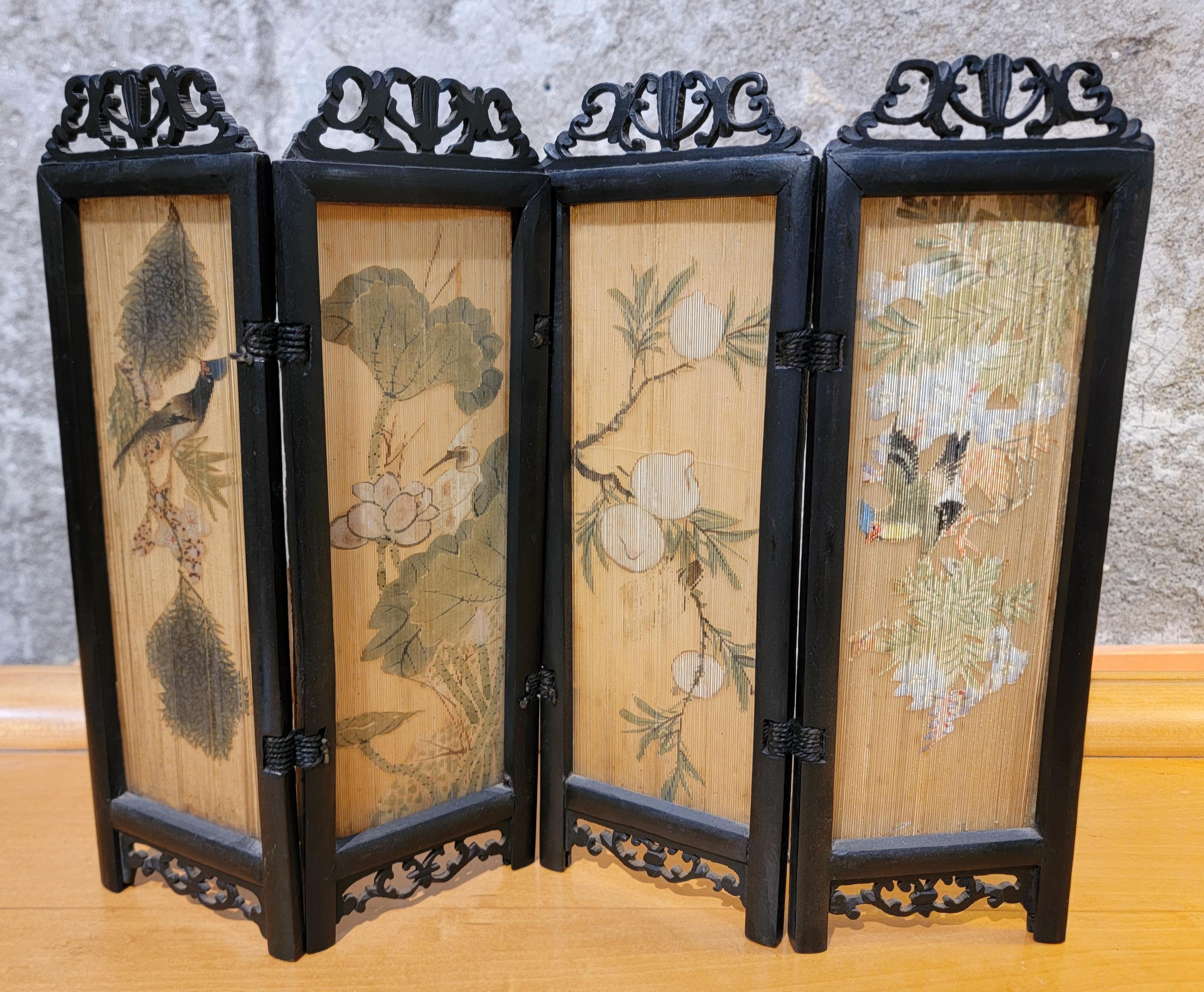 Insolito schermo pieghevole da tavolo. Quattro pannelli dipinti a mano con uccelli, frutta e fiori. Incisione parziale a mano sulla cornice in legno. Sembra che si tratti di palissandro, ma non è confermato. Una decorazione da tavolo bella e