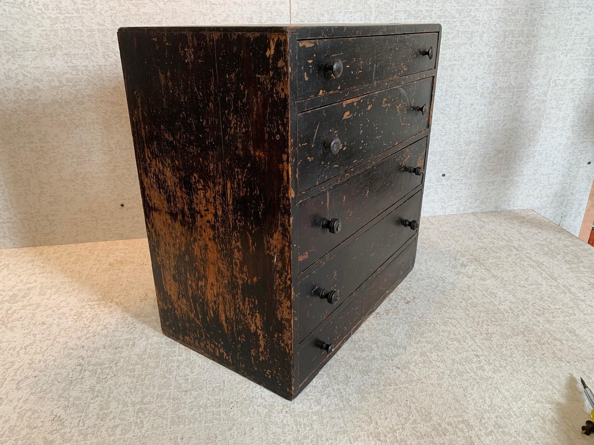Five-drawer typeset cabinet in birch with pine secondary wood. Mixed metal and wooden knobs. Some drawers retain dividers with remnant paper labels. Dark original finish.
