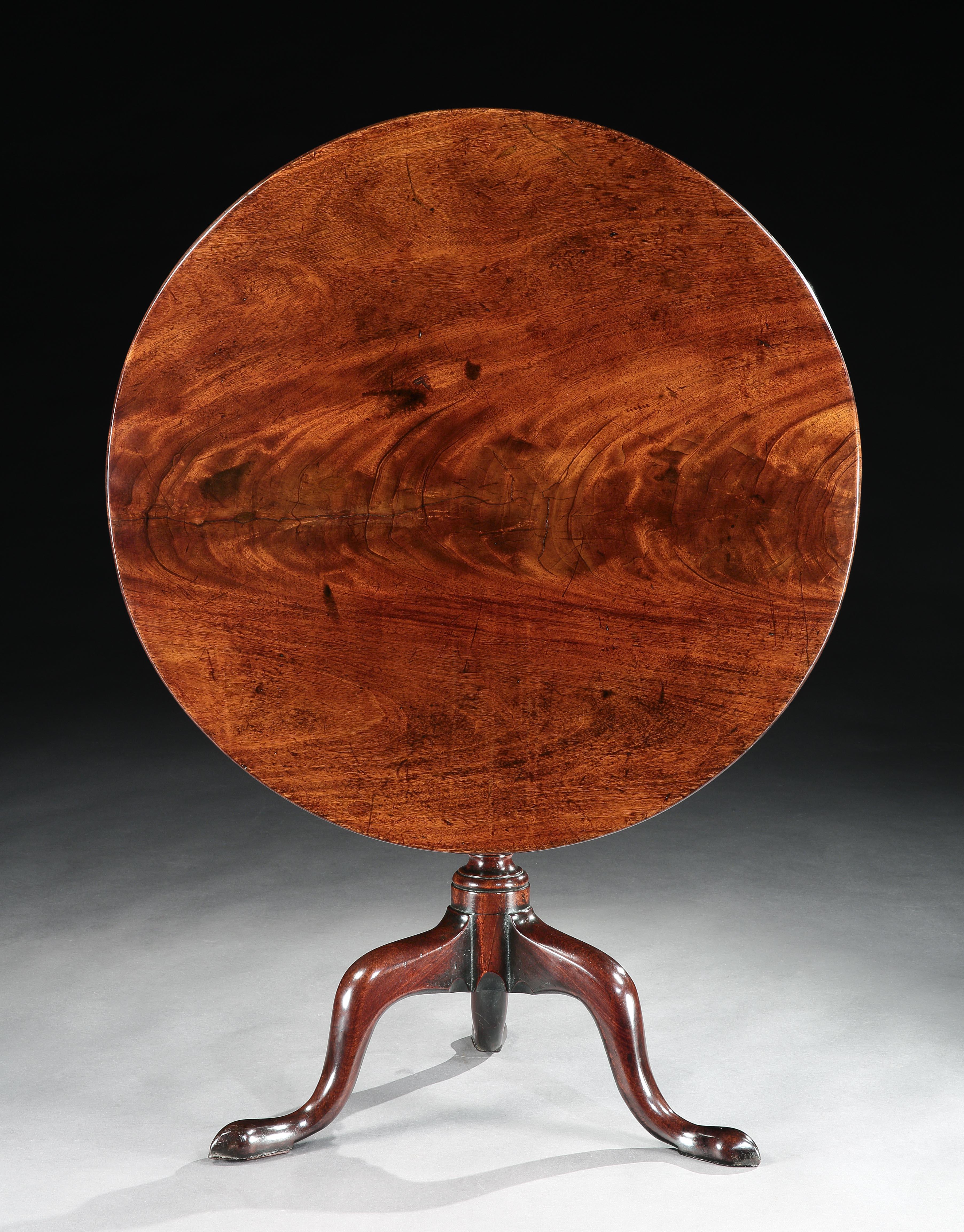 The circular 2 cm/0.75in thick, tilt-top is made from a solid piece of mahogany with beautiful flame figuring. Unusually, the tilt-top mechanism and brassware are original. The stem with fine column and vase shaped turnings carved with ring and