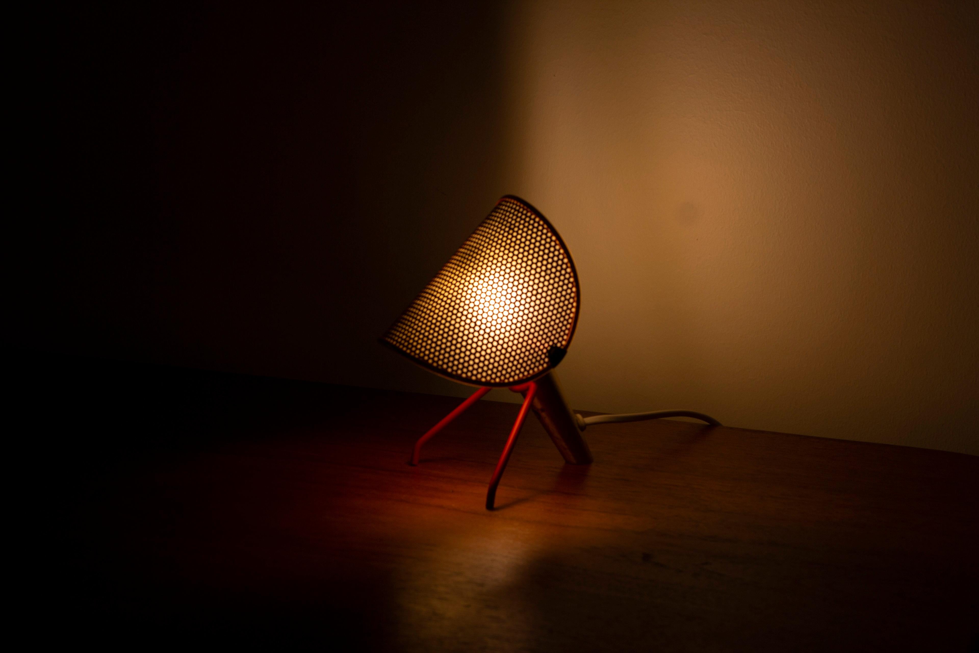 Decorative table/wall lamp designed by Ernst Igl. Produced on license by Falkenbergs belysning during the 1950s. Made from red lacquered steel and aluminum as well as polished brass. The perforated diffuser is adjustable in angle. Light switch on