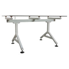 Tavolo con piano in vetro smussato e supporti in metallo