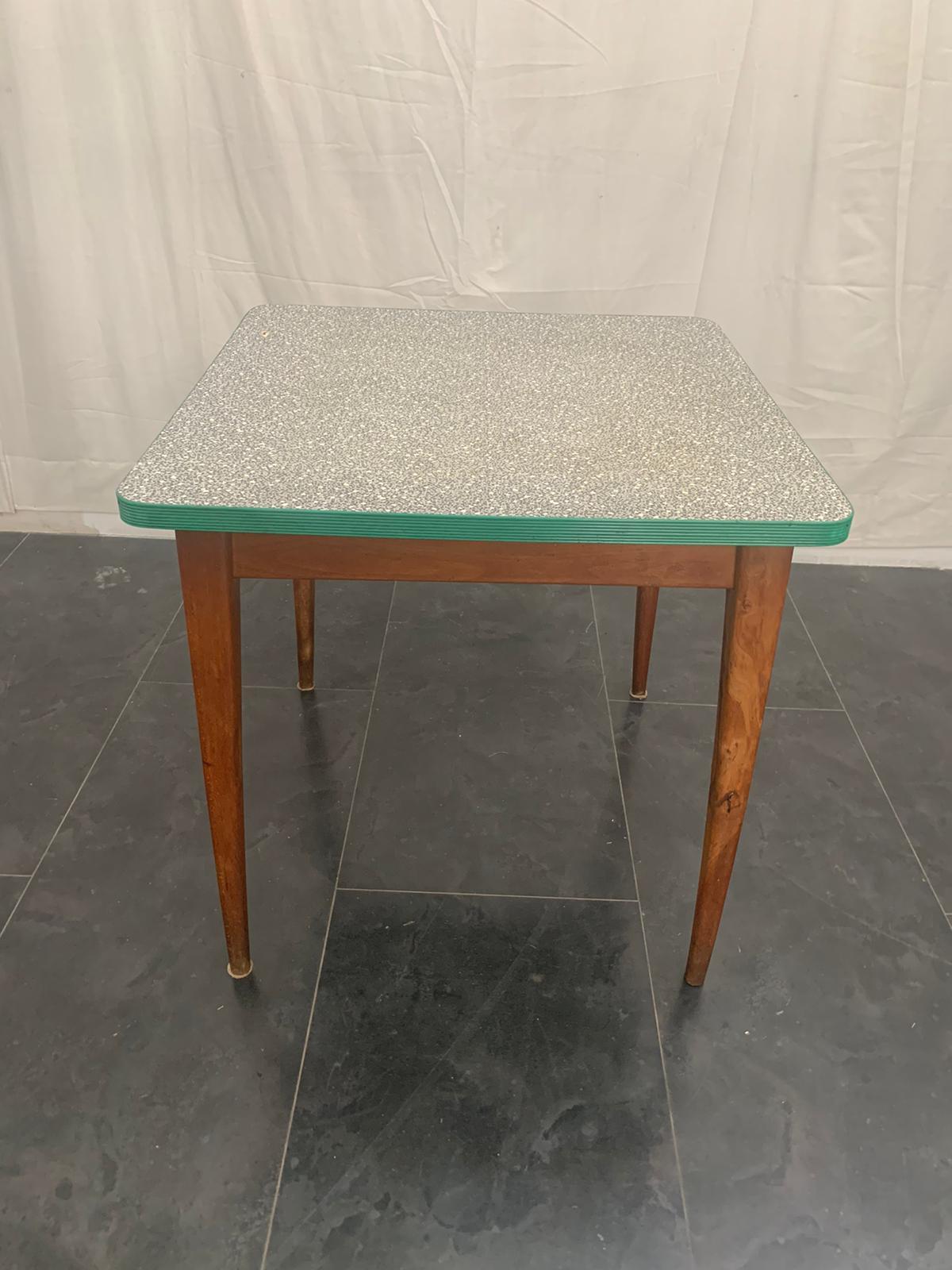 Table from the 1950s in cherry wood with top in laminate weave mosaic edged in plastic profile green color.