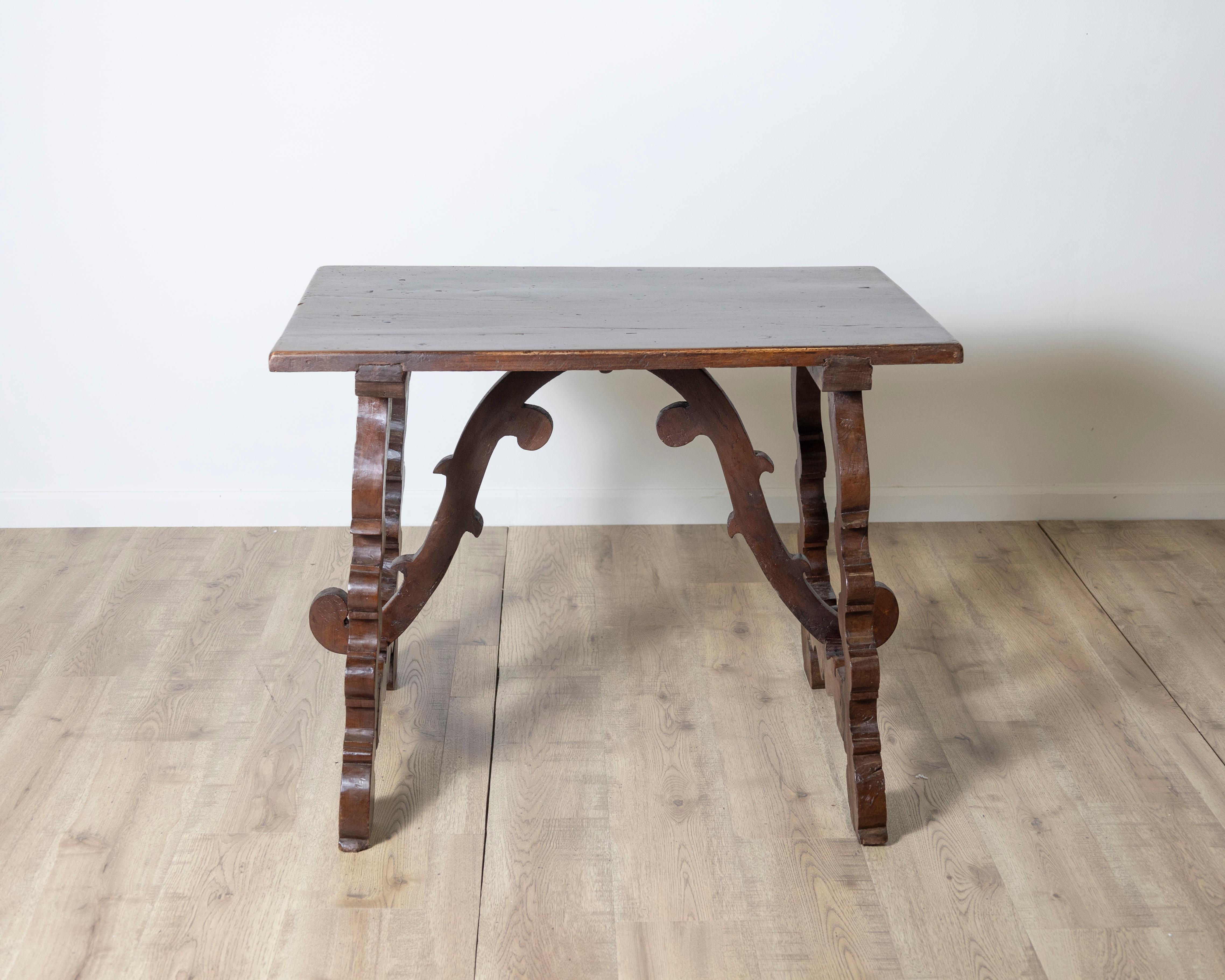 This elegant 18th-century Italian table from Central Italy is a striking example of period craftsmanship in solid walnut. Featuring beautifully carved lyre shaped legs and a shaped central stretcher, it reflects the influence of Baroque design with