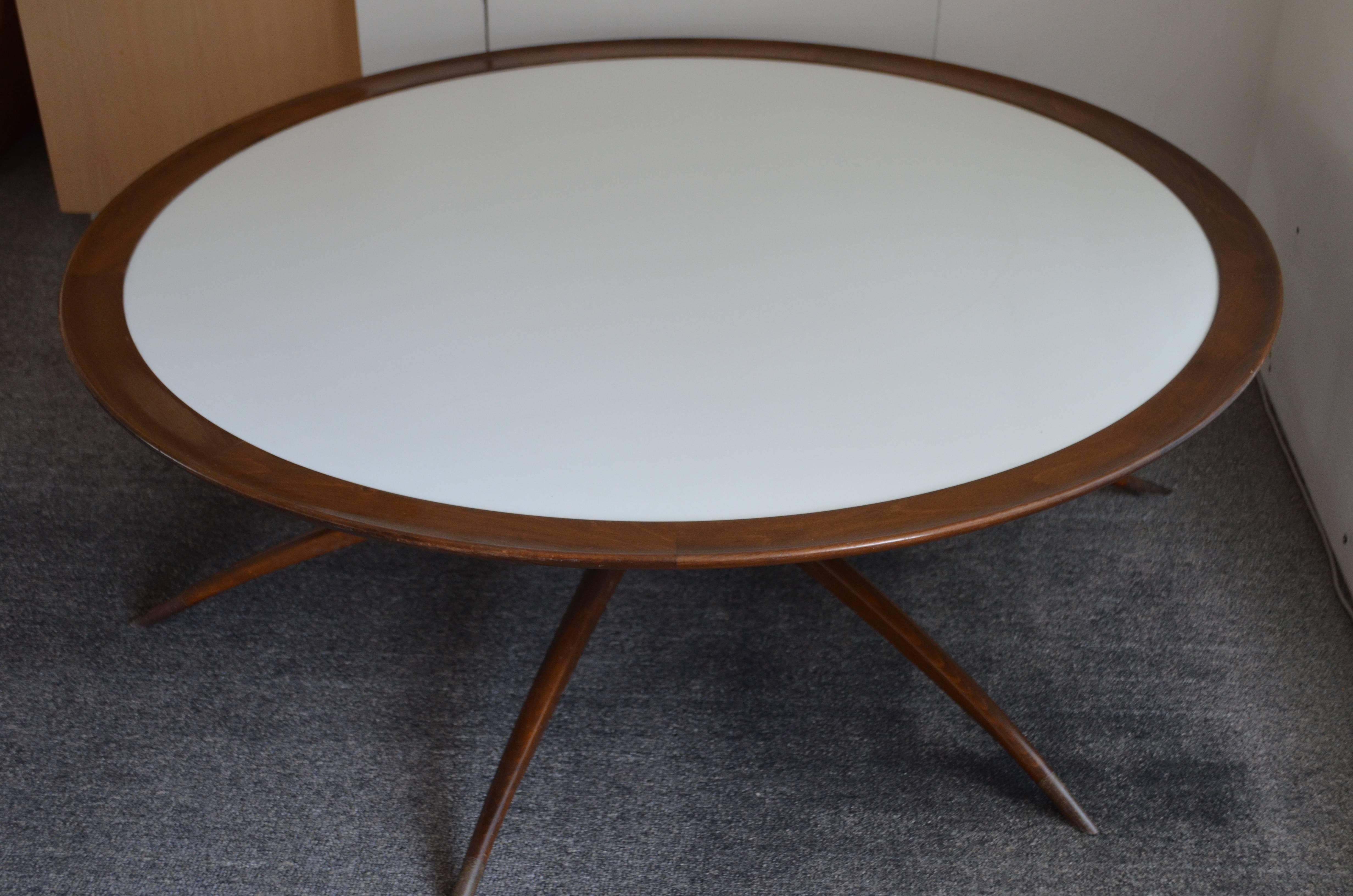 Danish coffee table with spider leg base and milk glass top with walnut surround. Attributed to Carlo di Carli. Spider legs of the base are tipped in brass. Base folds up neatly for easy transport. Milk glass top with walnut surround is stunning. An