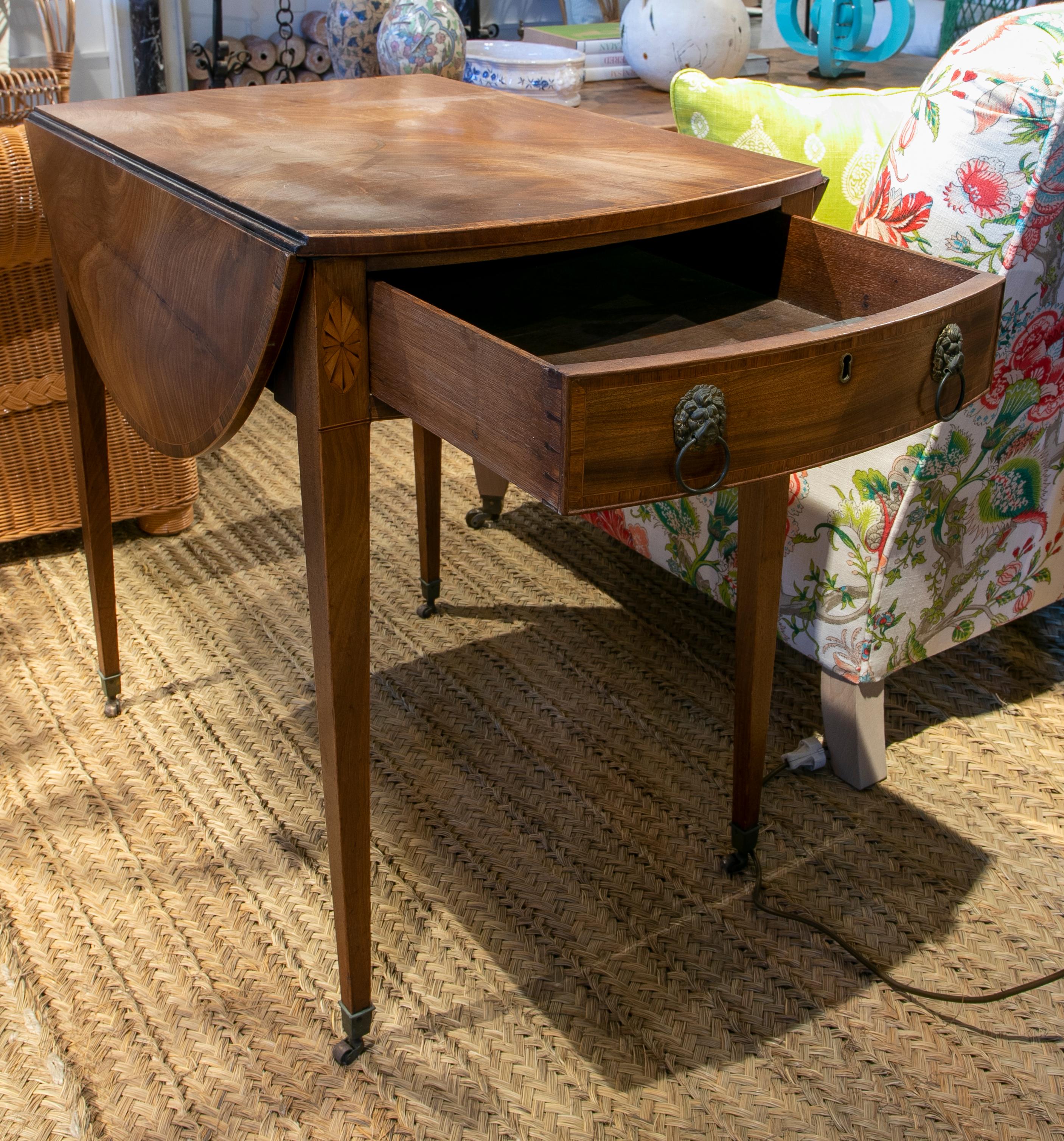 Table with wings and drawers on the sides with folding laterales and handles 
and lion's head handles and legs with brass wheels.