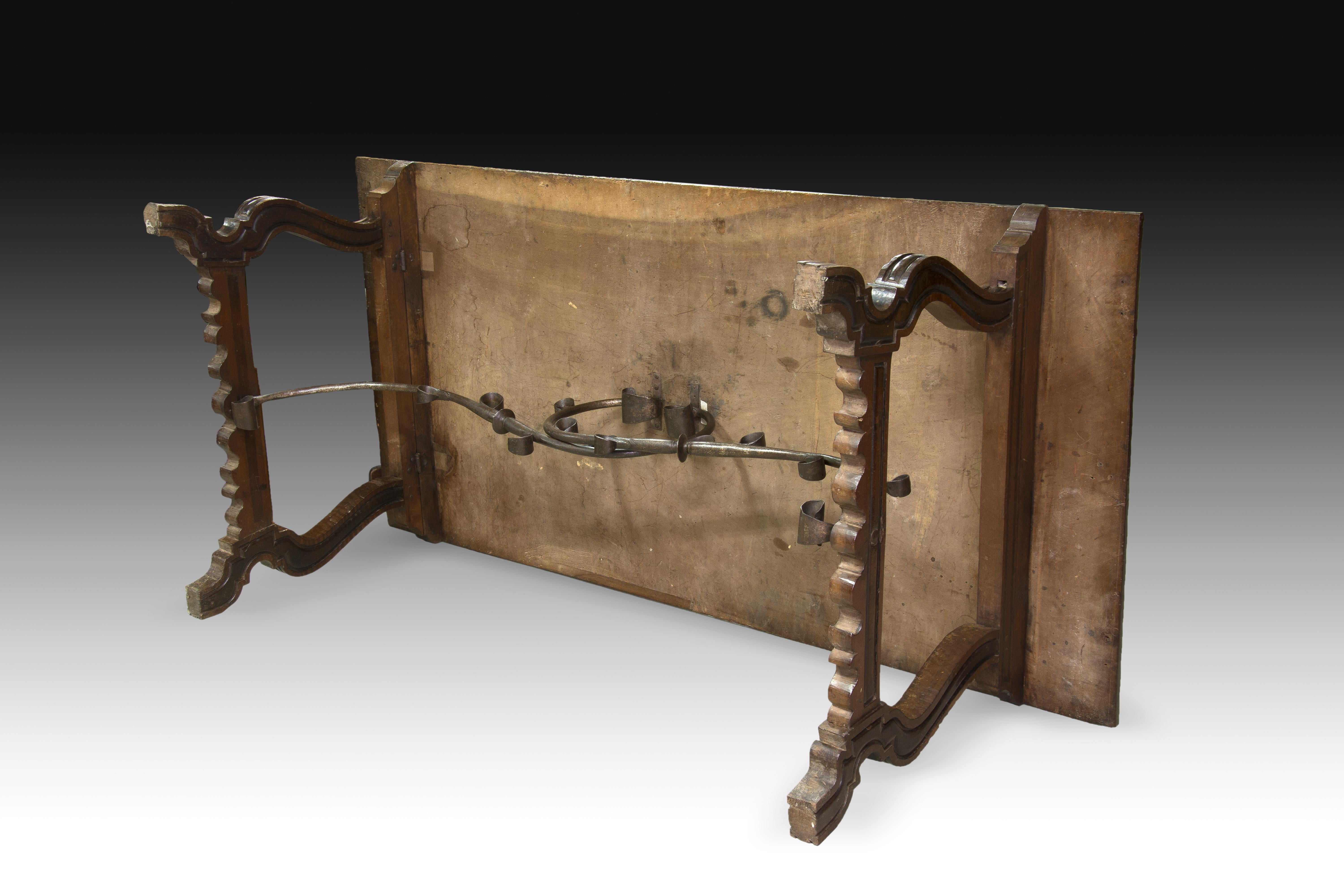 Spanish wooden table with lyre legs and iron fasteners. 18th century.
The two lyre legs that support the table have wavy lines in the lower area and some shapes on the sides reminiscent of those of French cabriolet. Both are joined with an iron