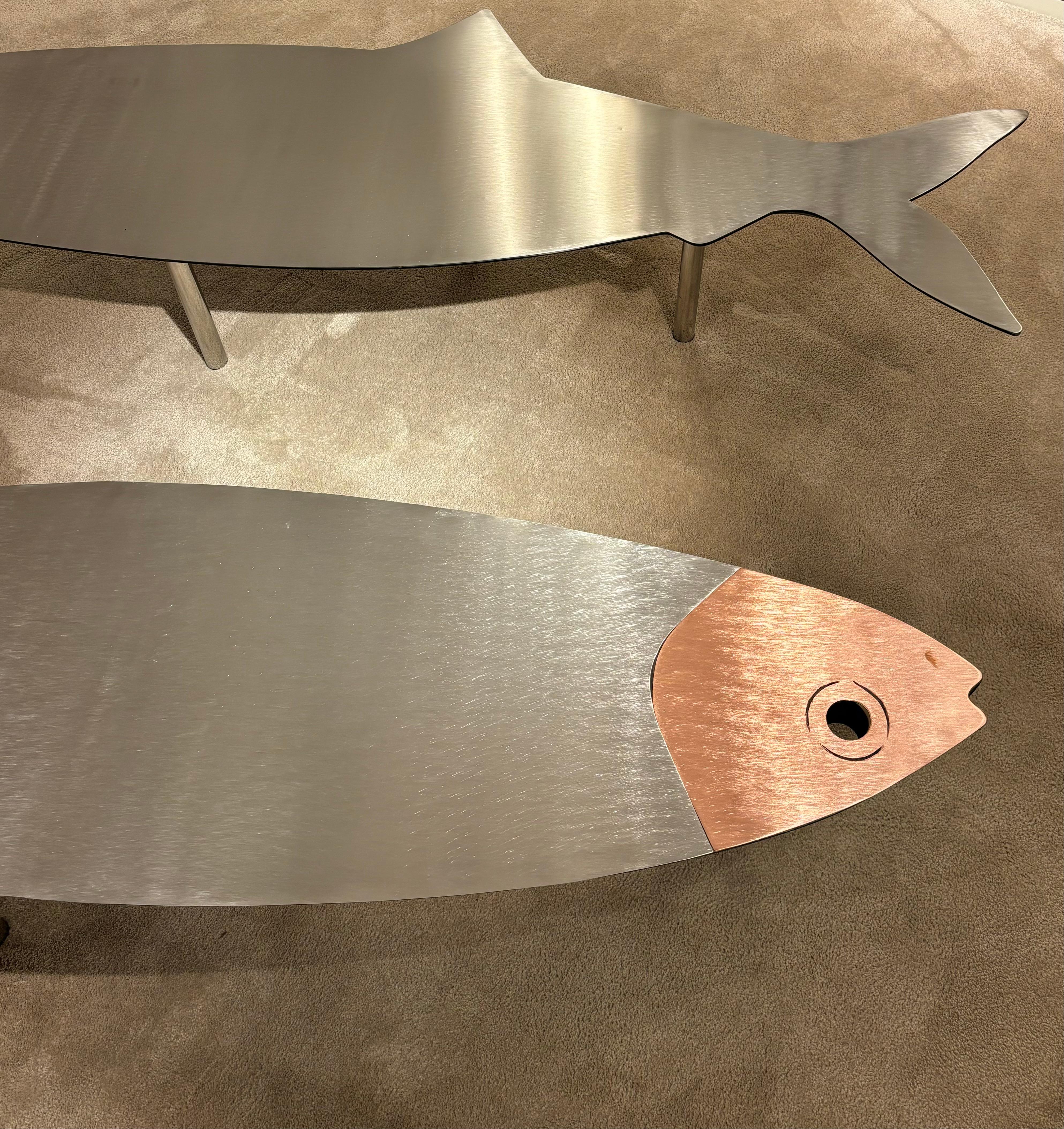Playful yet sophisticated, this remarkable pair of Italian coffee tables from the 1960s embodies the experimental spirit and bold creativity of mid-century design. Each table is crafted in the whimsical shape of a fish, its elongated brushed metal