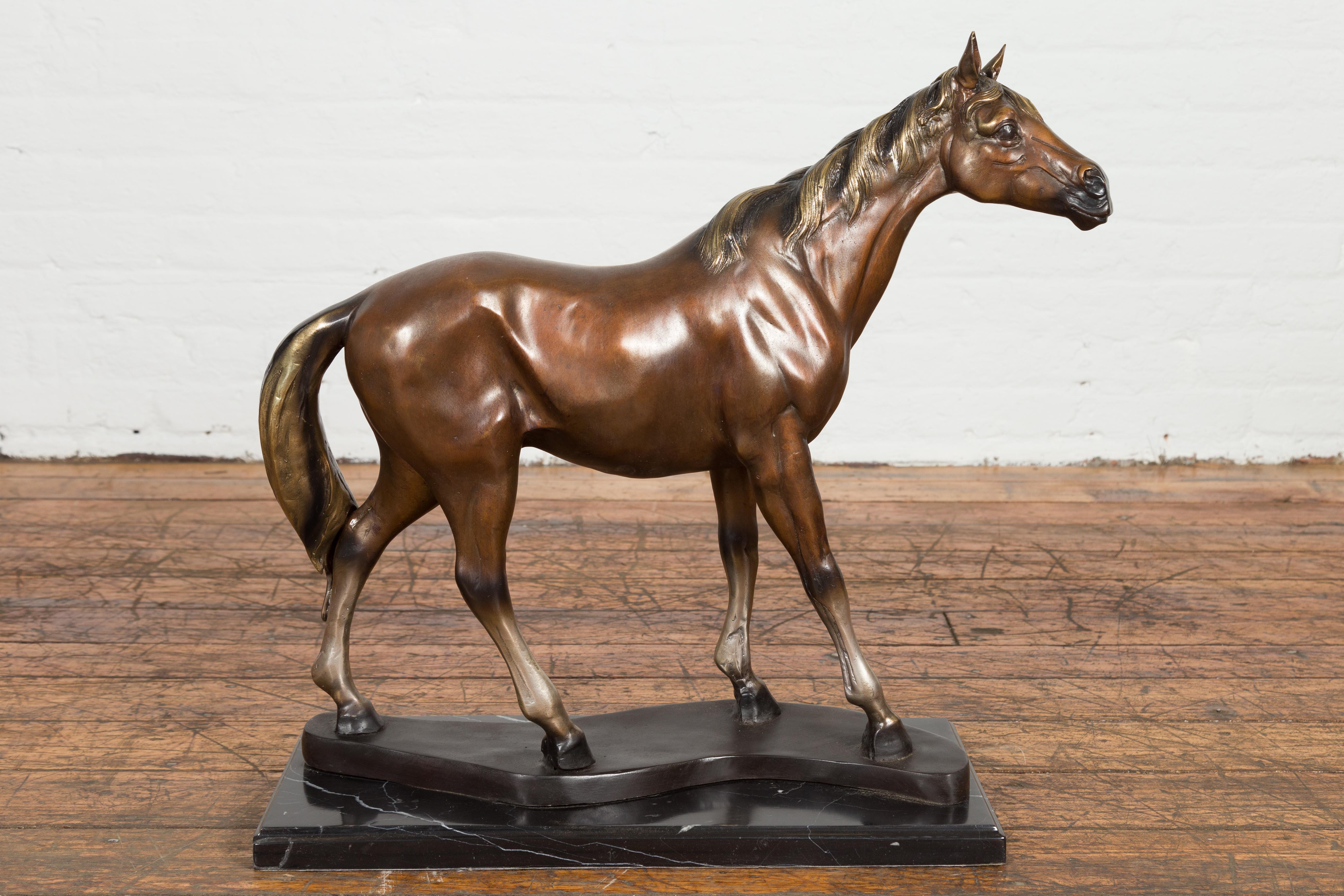 A lost wax tabletop bronze horse statue on black marble base. Exuding an air of regality and grace, this exquisite lost wax tabletop bronze horse statue is a testament to impeccable craftsmanship and artistry. Striding elegantly atop a resplendent
