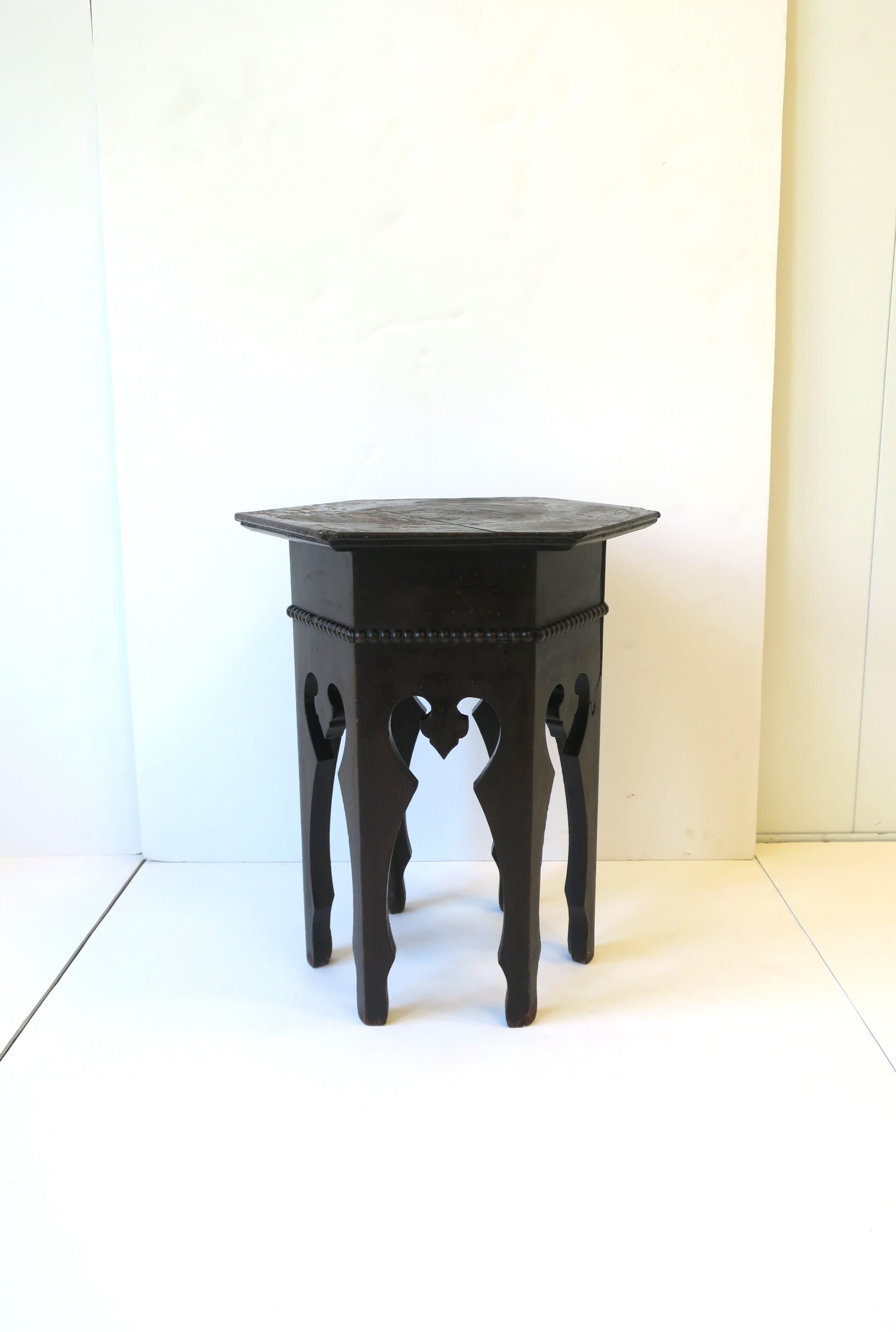 A dark rich brown Moroccan tabouret drinks or side table with traditional Moorish design, circa early-20th century, Morocco. This wood table is hand-painted in a rich dark brown hue and has a round hexagon top and base. Dimensions: 13.63