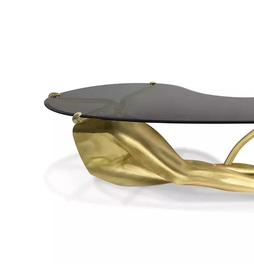 Ajoutez du sex-appeal et de la fantaisie à votre salon avec la table cocktail Tabu. Les pieds sensuels en feuilles d'or s'étendent sous un plateau en verre bronze sophistiqué pour créer l'objet de conversation parfait pour votre prochain