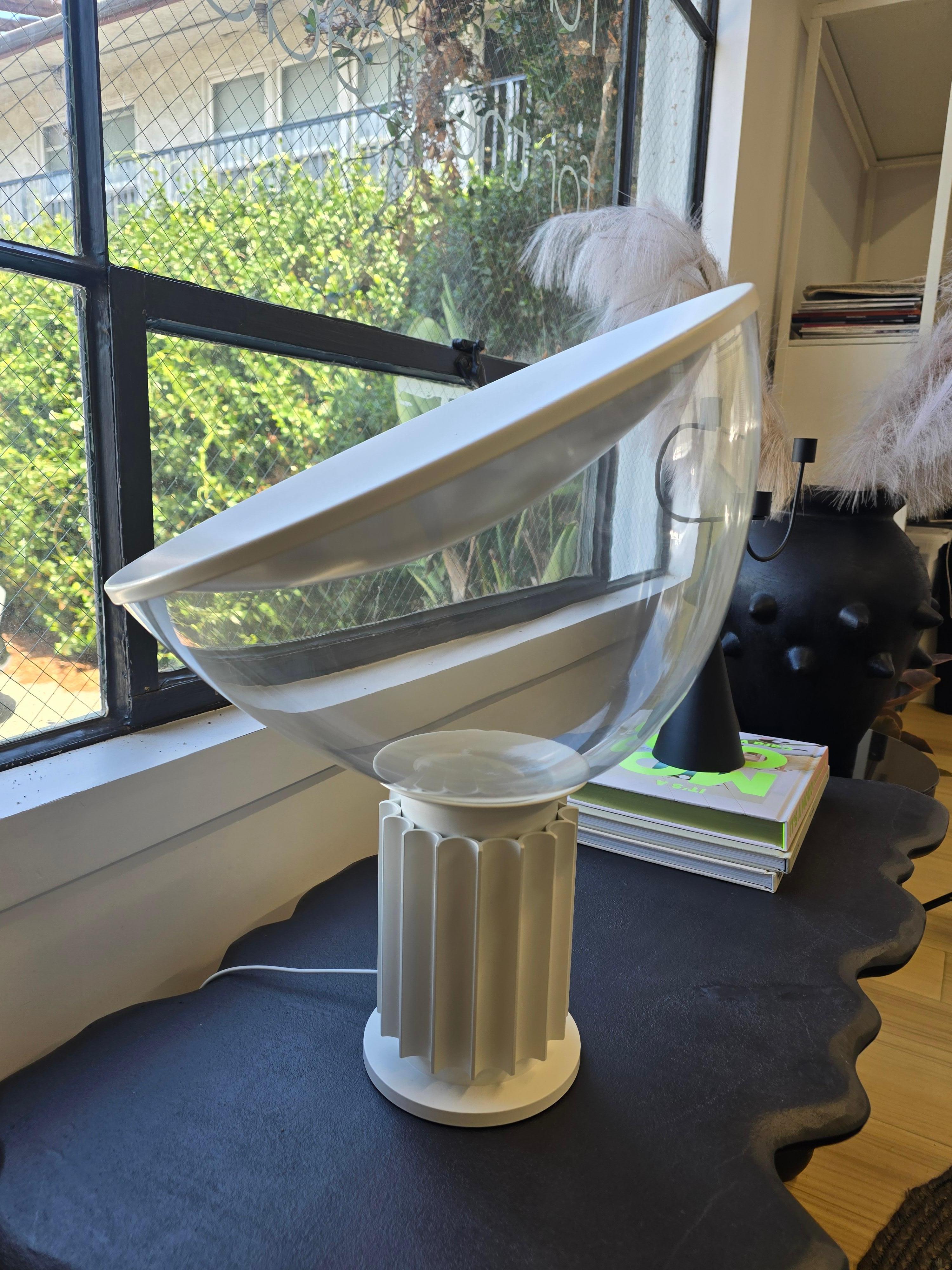 Taccia
Designed by Achille and Pier Giacomo Castiglioni, 1962
Table lamp providing indirect and reflected light. Reflector in painted aluminium, gloss white on the outside and matt white on the inside. Directionable diffuser in transparent