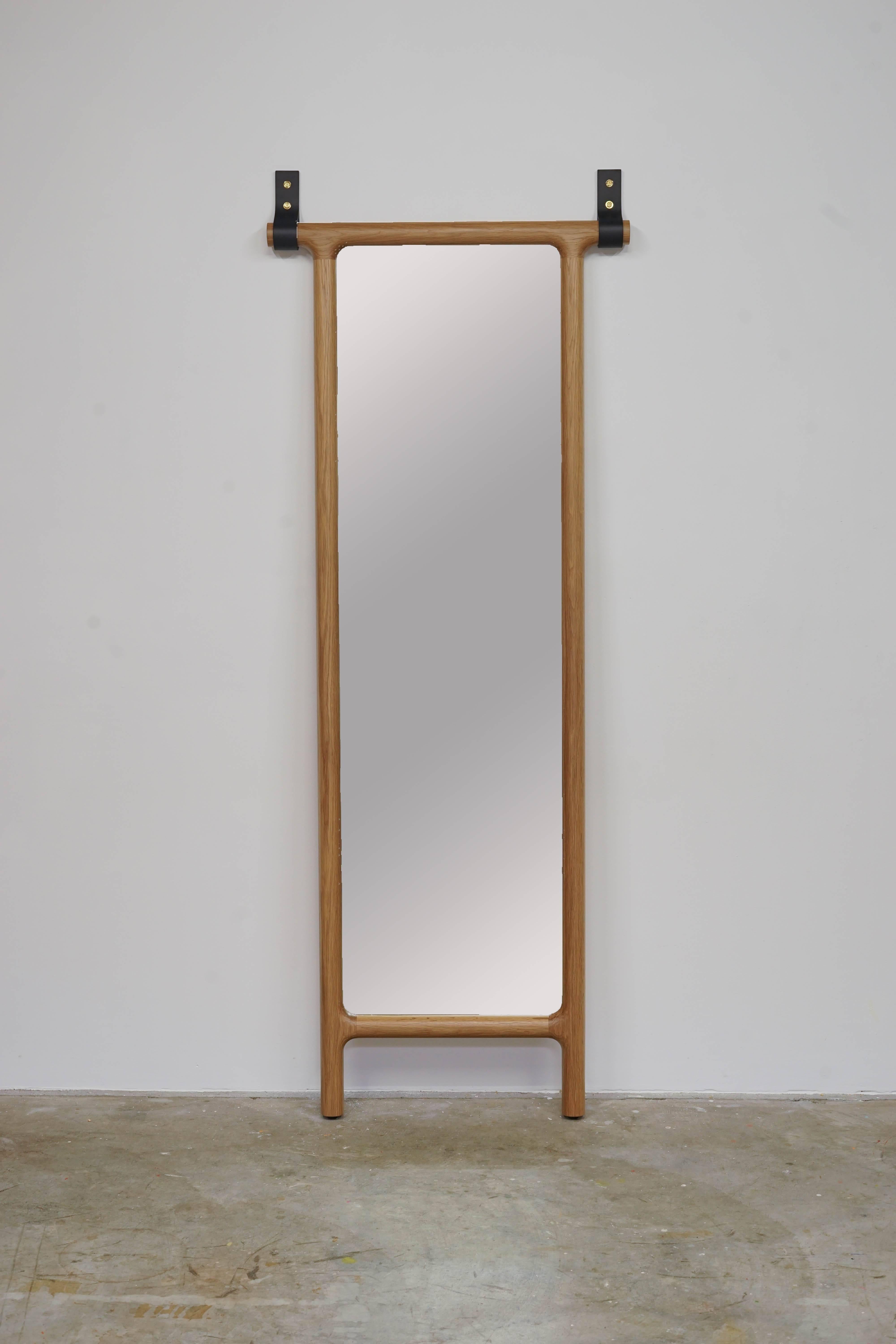 Leaning floor mirror with thick leather straps that help keep it upright.

Walnut mirror can be shipped within 3 weeks. Custom variations require lead time of 15-16 weeks.