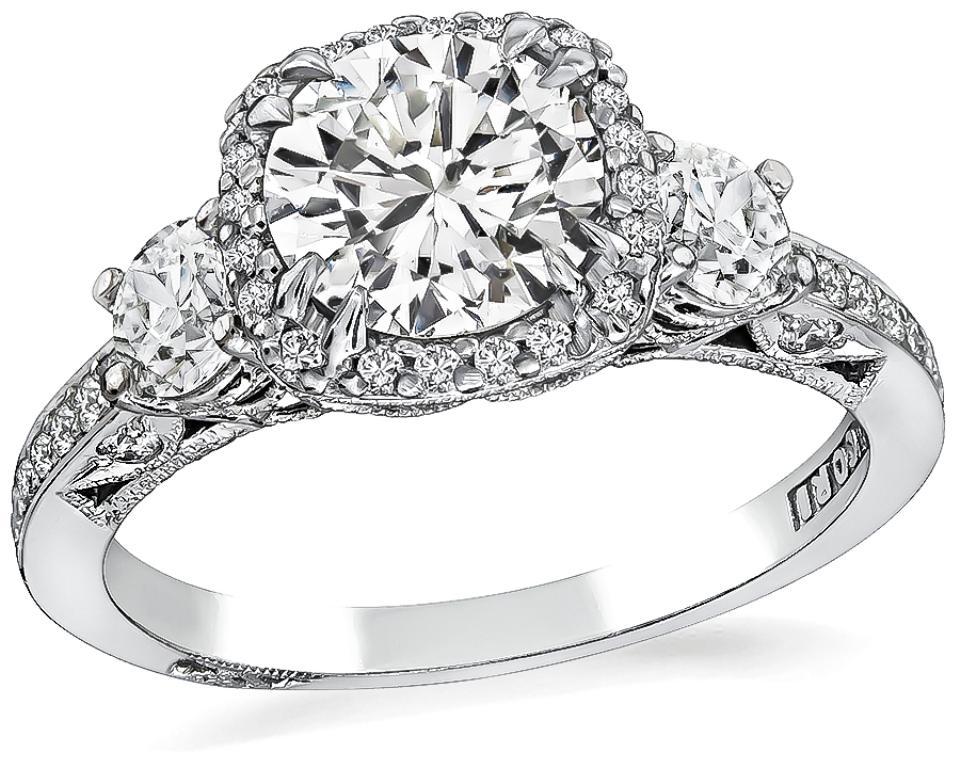 This elegant 18k white gold engagement ring and wedding band set by Tacori, centers a sparkling GIA certified round cut diamond that weighs 1.10ct. graded H color with SI2 clarity. The center diamond and the wedding band is accentuated by dazzling