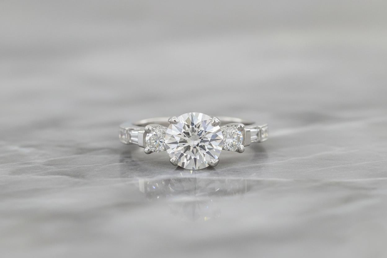 Un elegante anillo de compromiso semimontura Tacori, elaborado por expertos en platino y oro amarillo de 18 quilates, que muestra la característica mezcla de artesanía atemporal y elegancia contemporánea de la marca.

La montura presenta dos