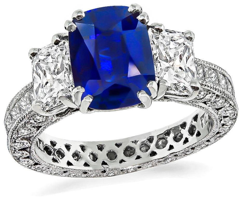 The ring is centered with a lovely cushion cut sapphire that weighs 2.74ct. accentuated by 2 radiant cut diamonds that weigh approximately 1.75ct. graded G color with VS clarity. The set is also adorned with sparkling princess and round cut diamonds