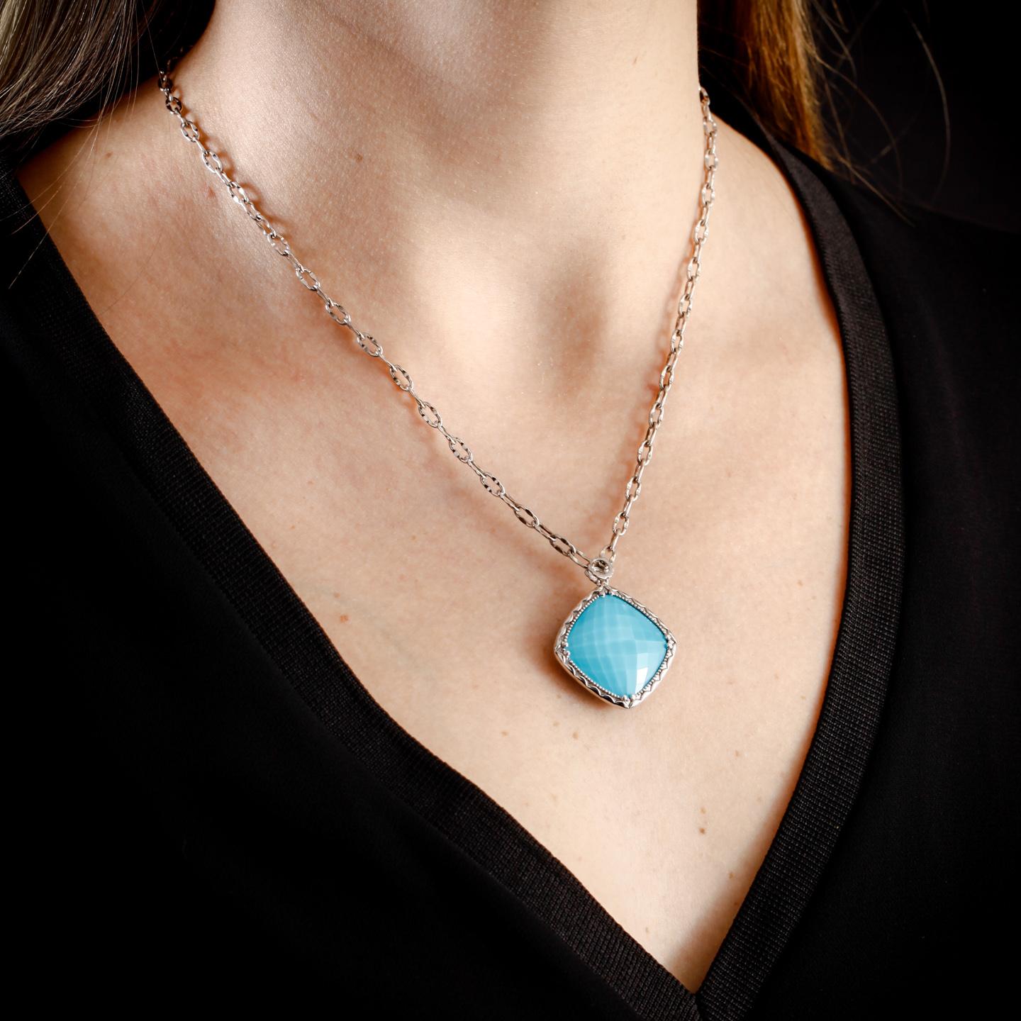 This Tacori Silver necklace is set with a 20x20mm cushion-shaped pendant of turquoise and clear quartz surrounded by silver. The Tacori stamp featured on the bale is 18k yellow gold. The silver Tacori chain is 18 inches long. This necklace is in
