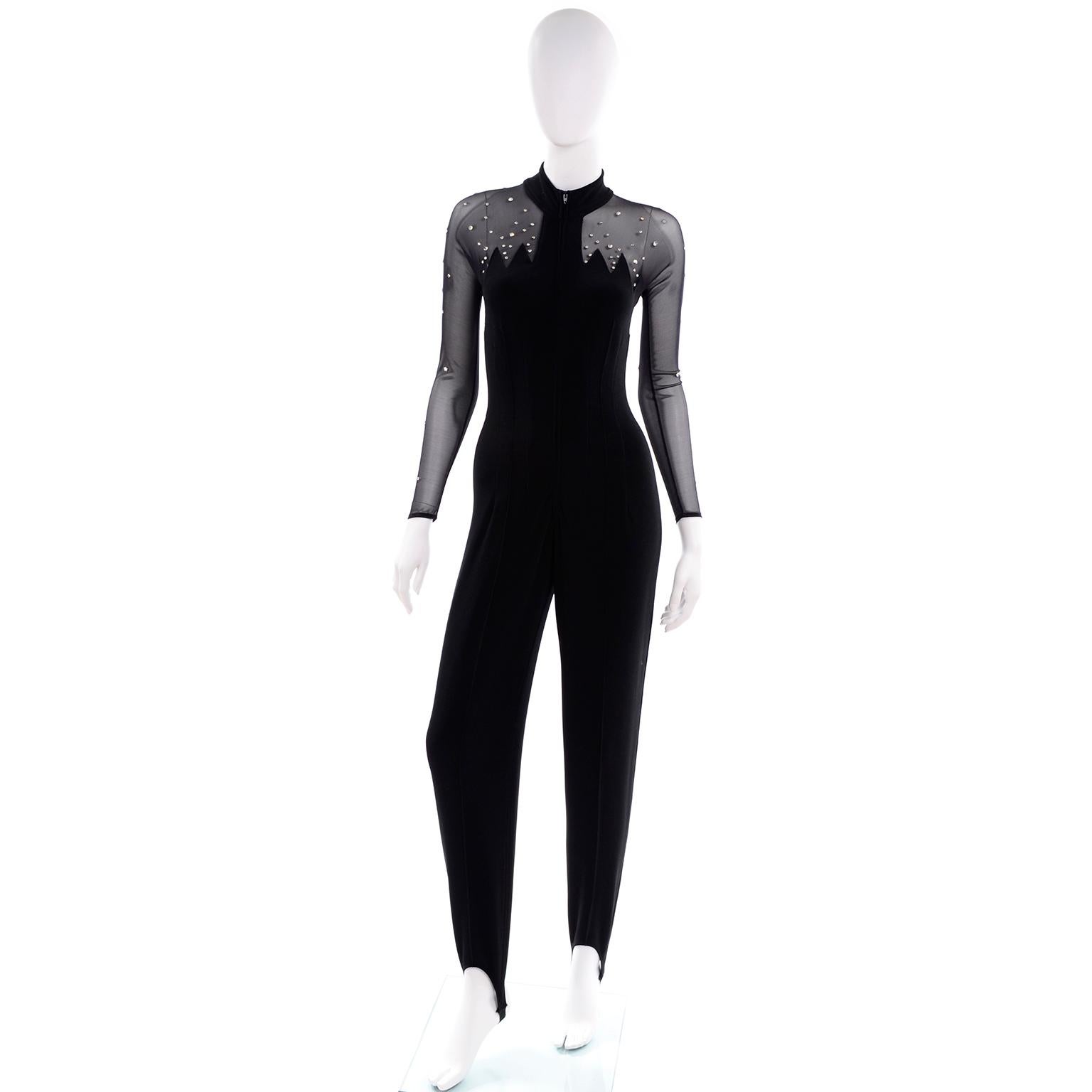 This stunning black stretch knit jumpsuit from Tadashi has sheer mesh on the sleeves and bodice and large panels on the back. This jumpsuit would make a great evening dress alternative! The front has zig zag detail at the shoulders and chest area