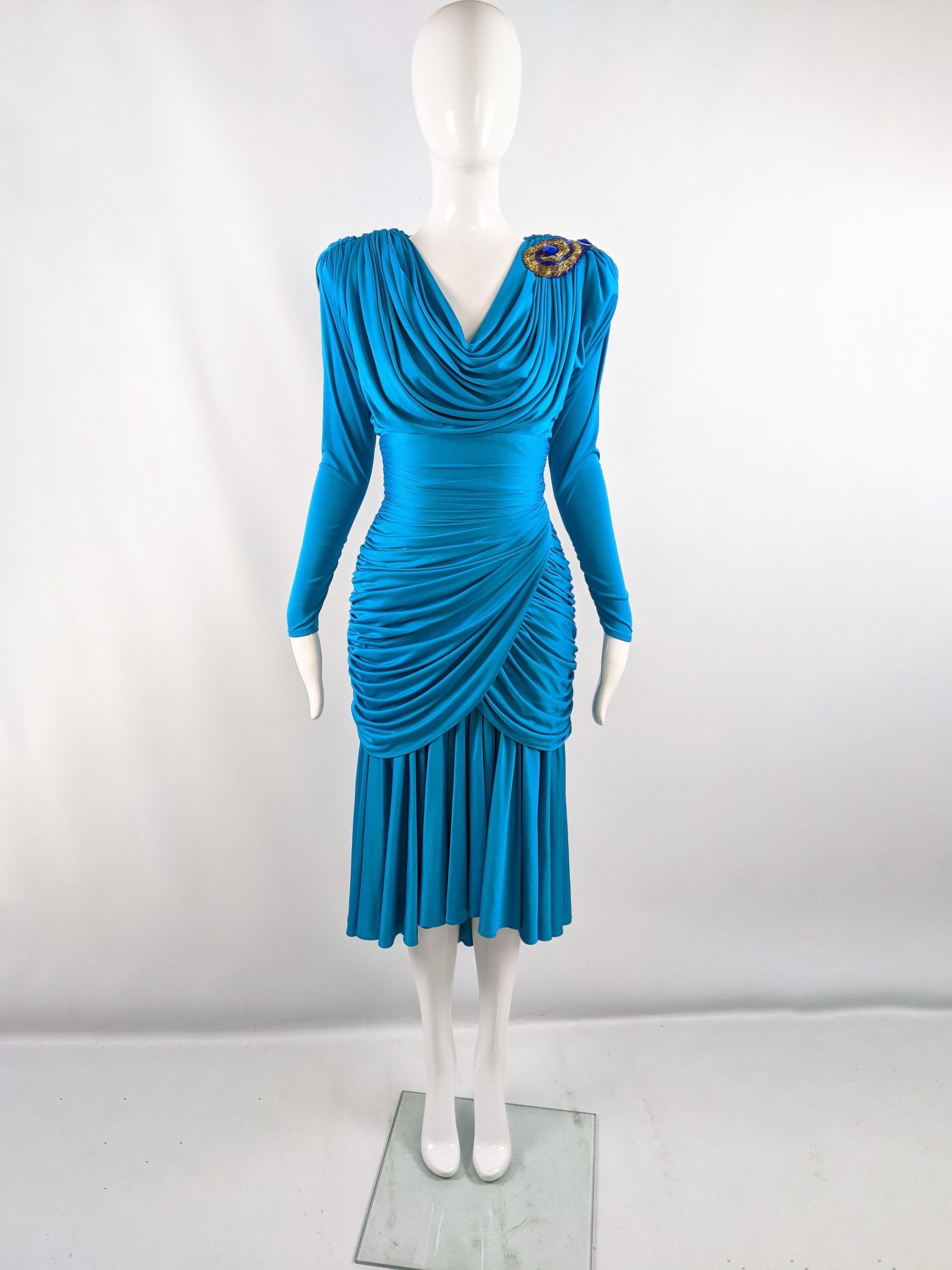 An incredible vintage womens party dress from the 80s by luxury fashion designer, Tadashi Shoji. In a blue slinky synthetic jersey which gives beautiful drape. The shoulders are padded and the bodice and hips are ruched which makes the waist appear