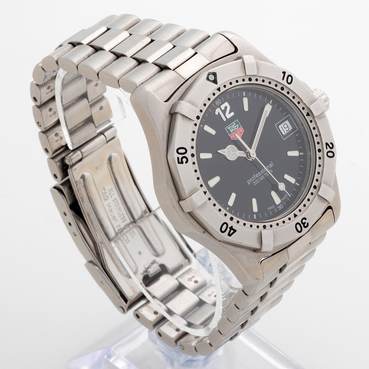 Nuestro Tag Heuer 2000 profesional de cuarzo neo vintage y reconocible al instante, referencia WK1110-1, tiene la muy deseable esfera negra, caja de acero de 39 mm (sin corona) y brazalete. Nuestro ejemplar muestra ligeros signos de uso en general,