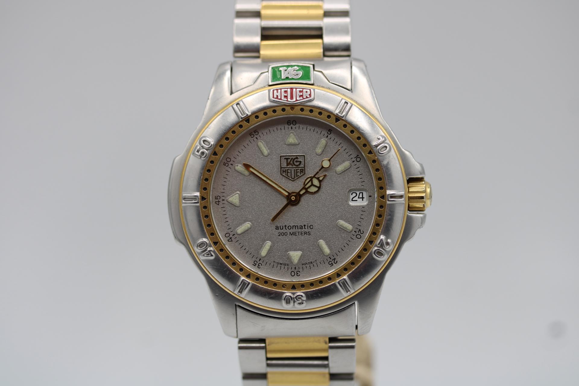 Este Tag Heuer, modelo WF2121-k, tiene caja de acero inoxidable de 38 mm, bisel giratorio unidireccional de acero inoxidable con grabados de intervalos de 10 minutos y reajuste chapado en oro, esfera plateada con una combinación de marcadores de