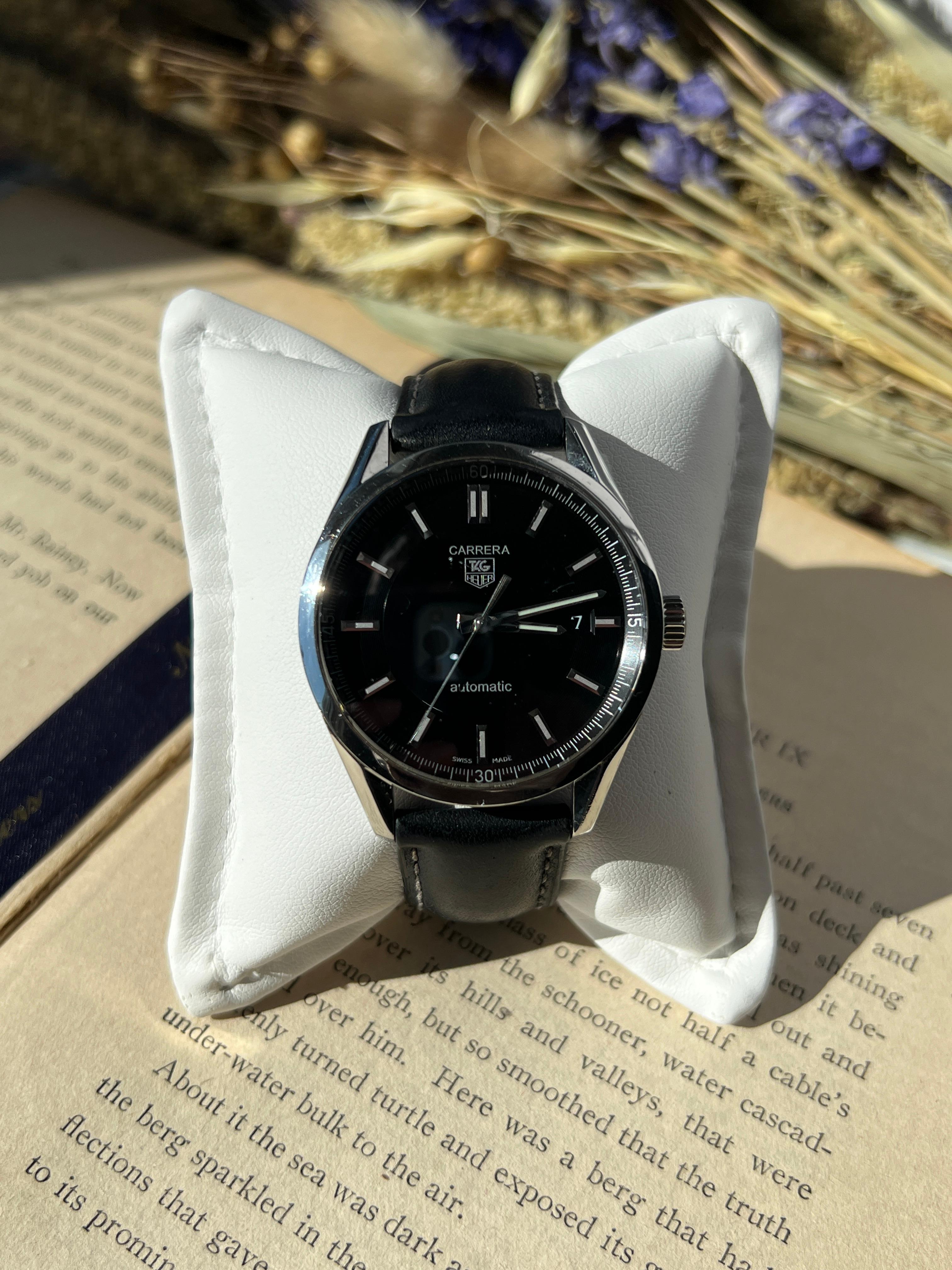 Diese TAG Heuer Carrera Automatikuhr, Modell #WV211B-2, ist eine klassische Mischung aus Präzision und Stil. Sie verfügt über ein schwarzes 1,5-Zoll-Zifferblatt in einem schlanken Edelstahlgehäuse. Sie wird von dem zuverlässigen Automatikwerk