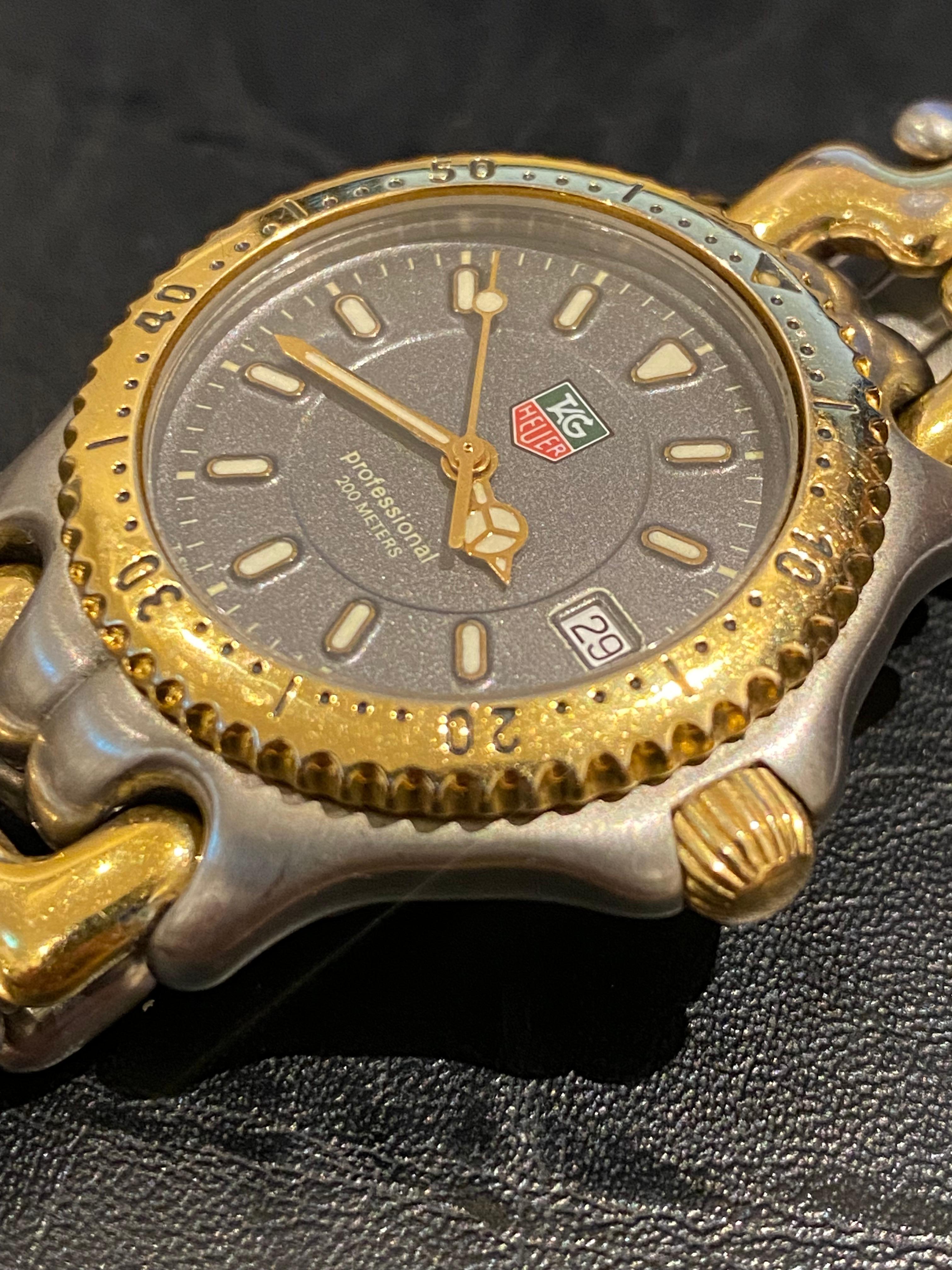 TAG Heuer Professional 200 Meters Quartz Gents' Watch features: 

36mm Stainless Steel Case,
in matte finish  
with screw down back & crown & 
gold plated rotating bezel 
signed & numbered at the back - ref WG 1220 KO

Striking Bluish Grey Dial with