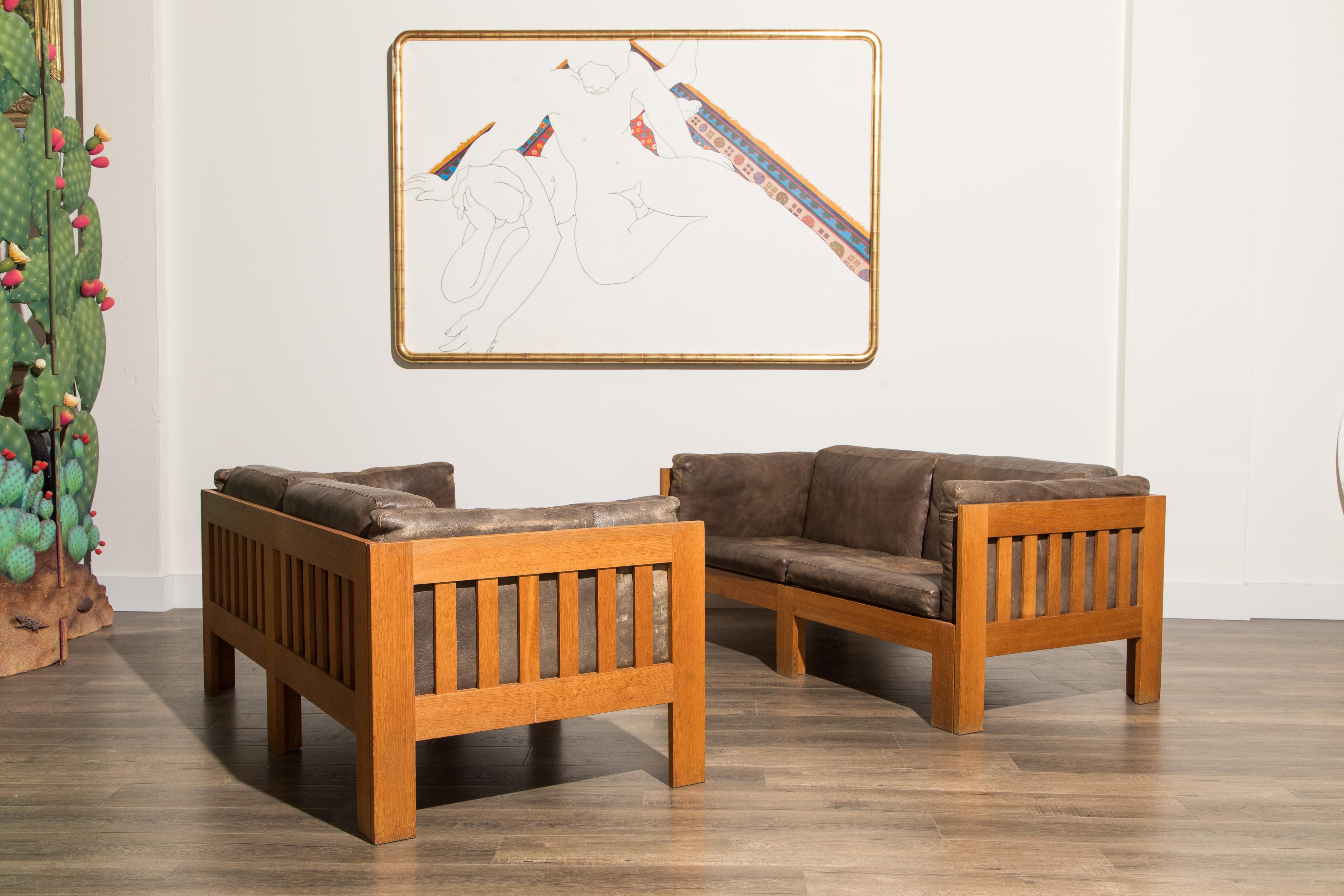 This beautiful pair of oak and leather Model TP632 settee sofas were designed by Danish architect and Professor Tage Poulsen in circa 1962. These Scandinavian Modern settees feature Mission style oak frames and thick durable heavy patina leather
