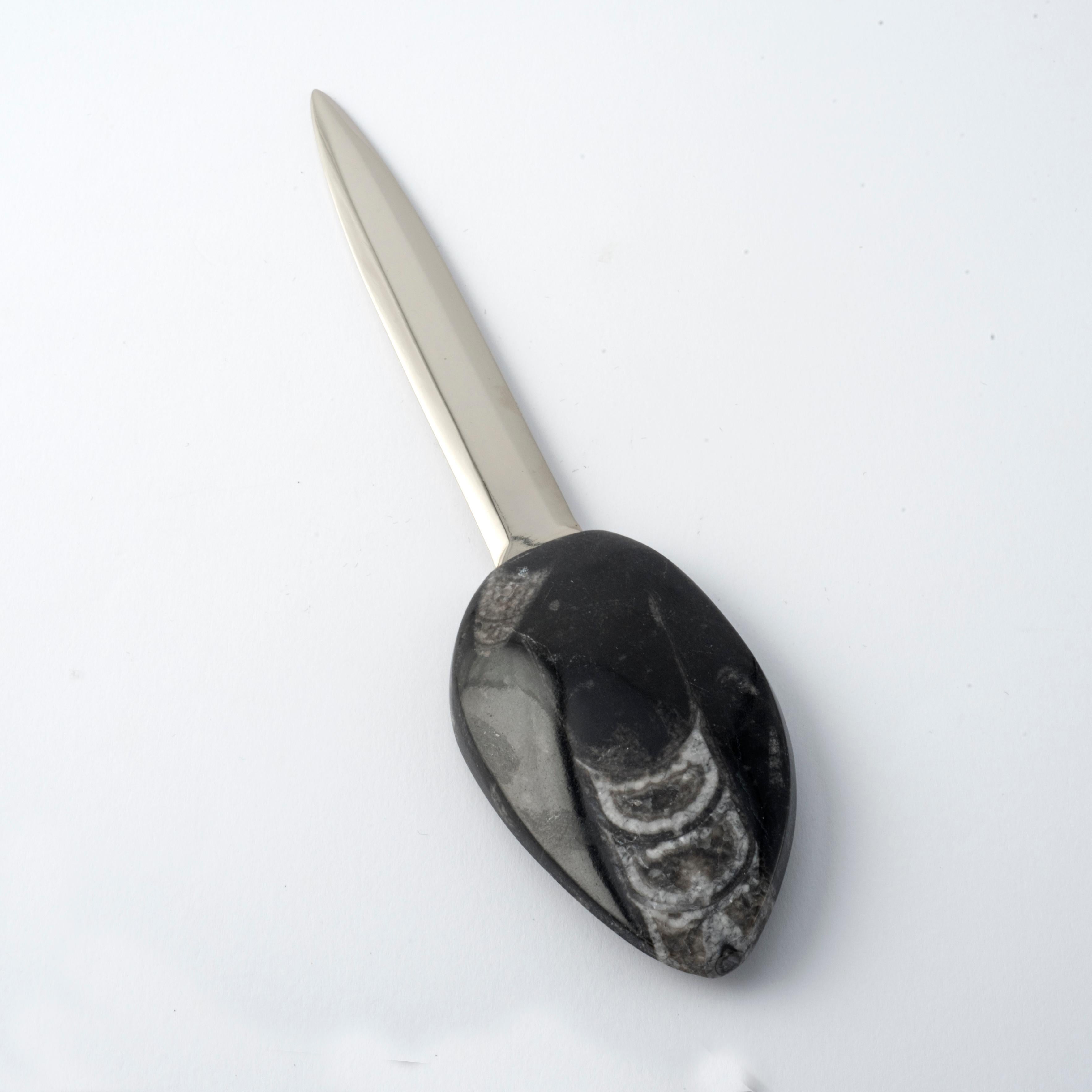 Aus der Sahara auf den Schreibtisch: Dieser handgefertigte Brieföffner ist mit einer authentischen Orthoceras-Fossilienmuschel mit kompakter, elliptischer Form, einer polierten Oberfläche und einzigartigen natürlichen Mustern verziert. 
Die