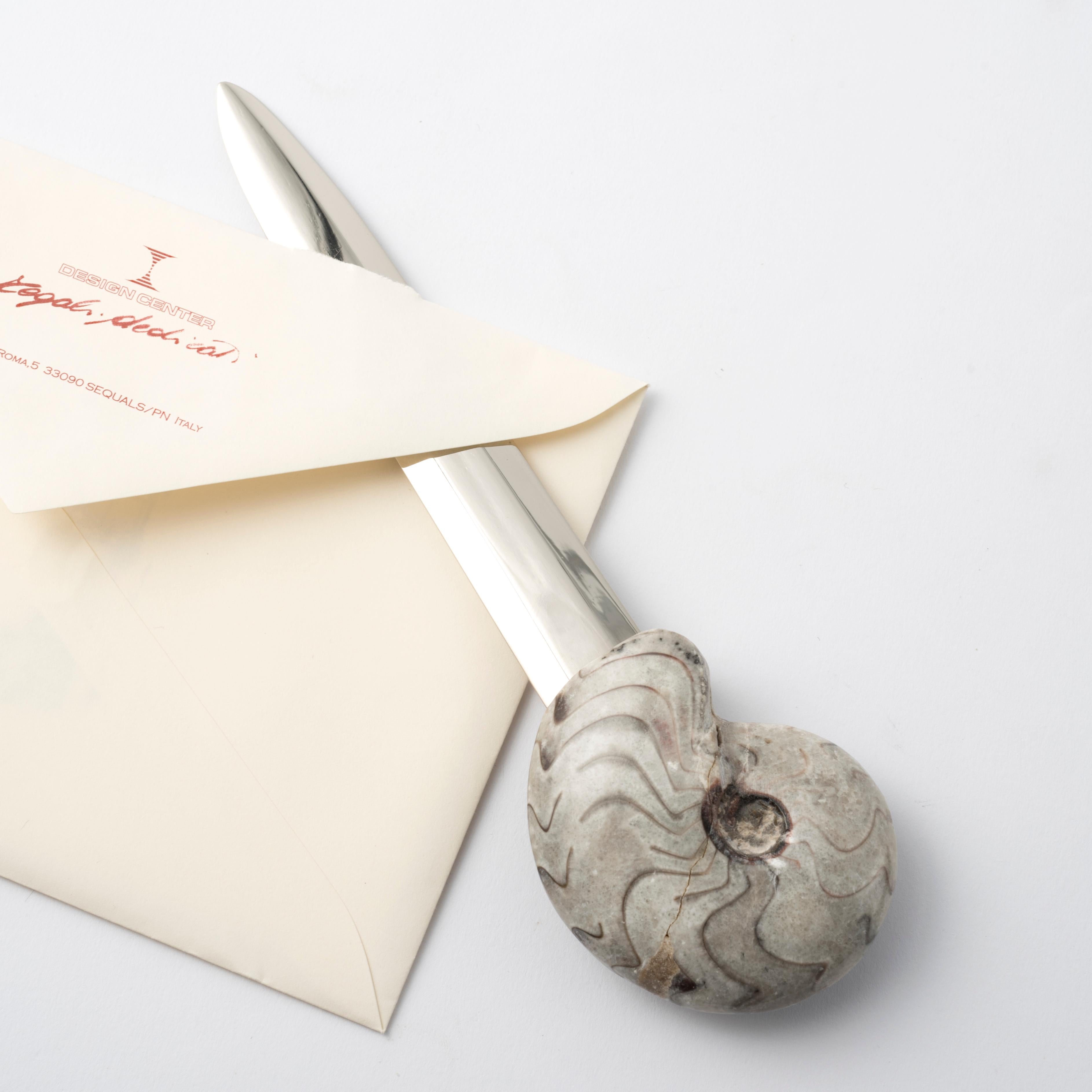Añada un toque de historia y sofisticación a su escritorio con este exclusivo abrecartas con auténtica amonita. 
Un accesorio de lujo con un diseño inconfundible, fabricado a partir de una auténtica concha fósil de Manticoceras, que data de hace 350