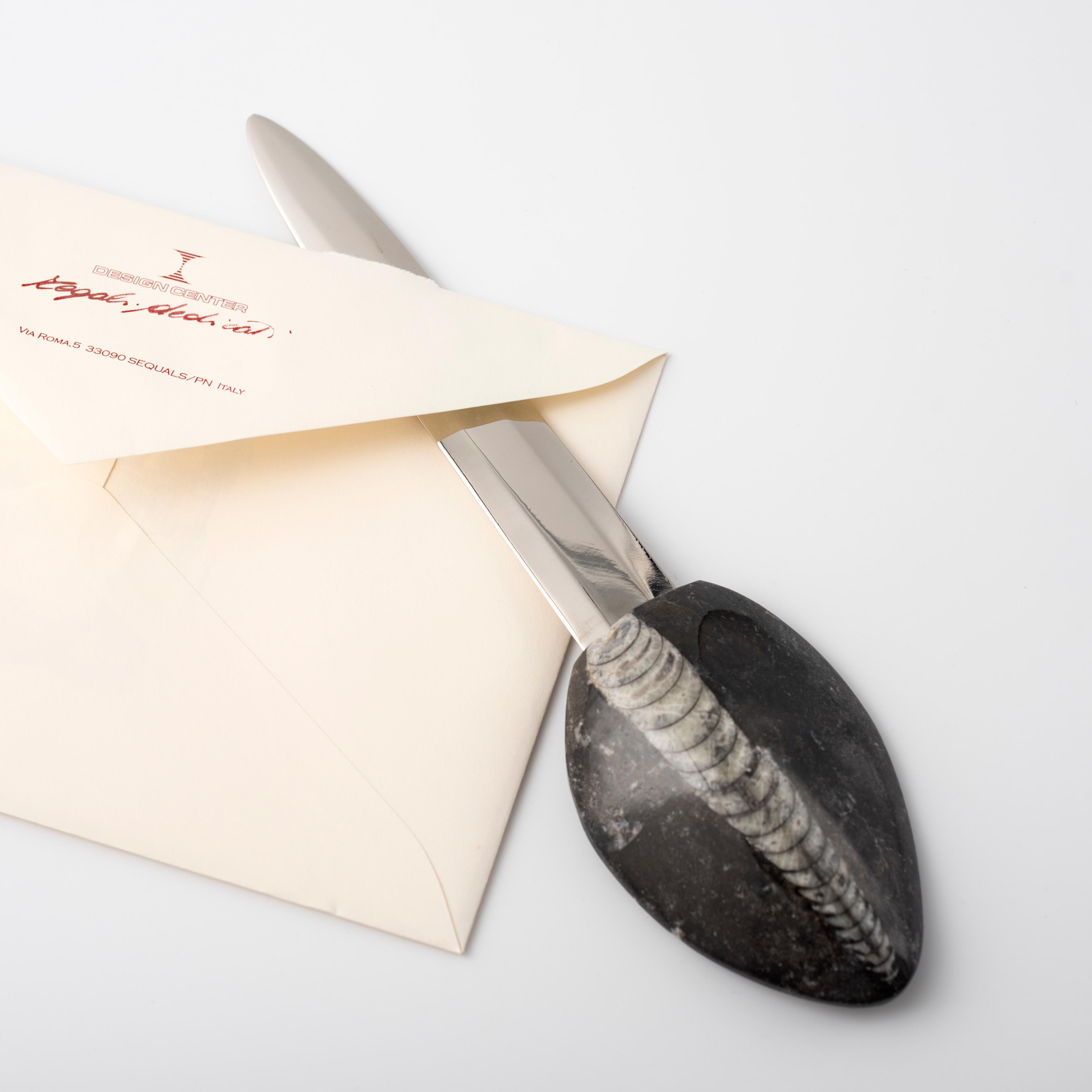 Eine leicht gewölbte konische Schale, die auf einer Gesteinsschicht liegt, wird  der einzigartige Griff des Brieföffners, ein unverzichtbares Schreibtisch-Accessoire. 
Entworfen von Nino Basso, dem Designer der Fossiline-Kollektion mit einzigartigen