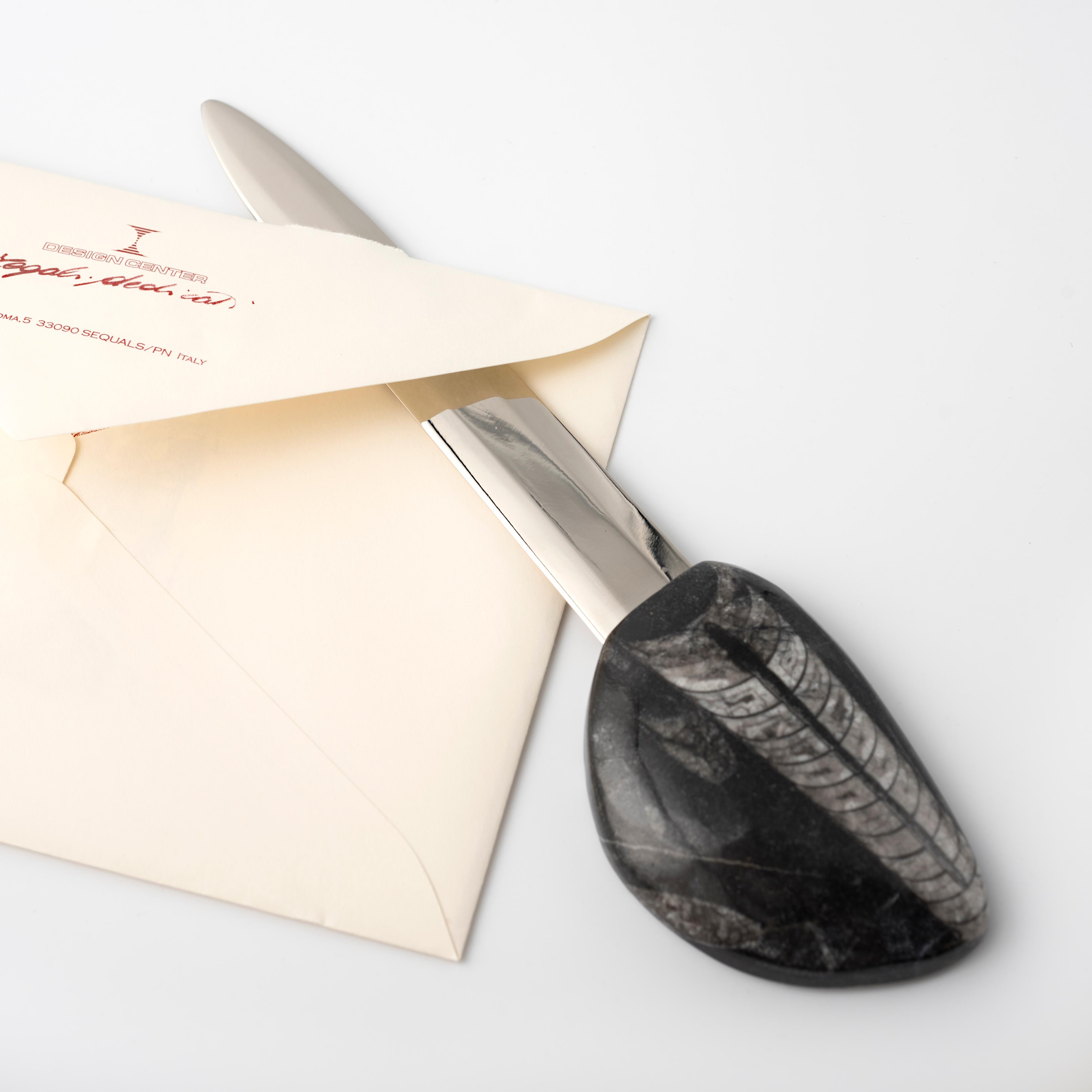 Eine leicht gewölbte konische Schale, die auf einer Gesteinsschicht ruht, wird zum einzigartigen Griff des Brieföffners, einem unverzichtbaren Schreibtisch-Accessoire. 
Der Brieföffner wurde von Nino Basso, dem Designer der Kollektion Fossiline,