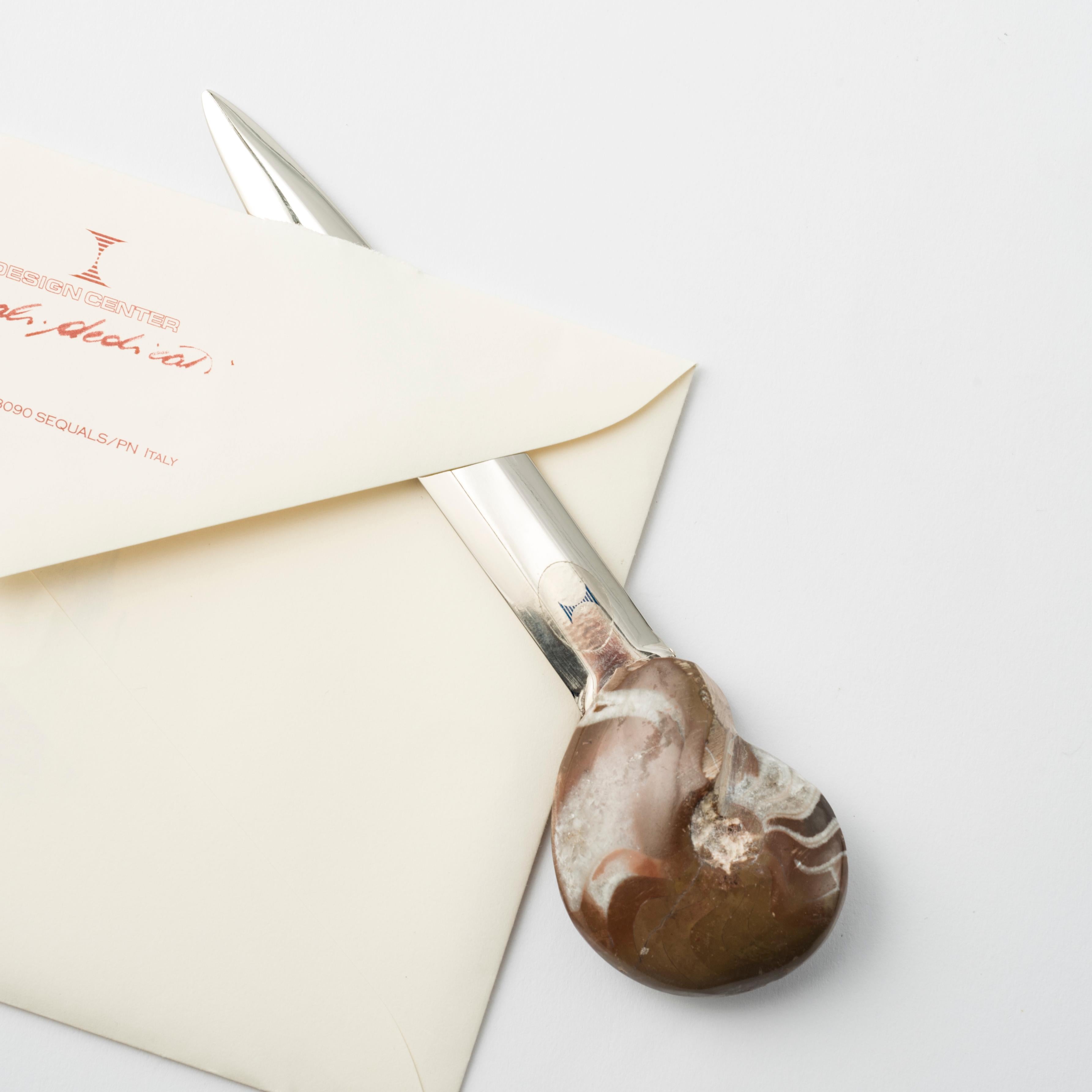 Verleihen Sie Ihrem Schreibtisch einen Hauch von Geschichte und Raffinesse mit diesem exklusiven Brieföffner mit echtem Ammonit. 
Ein luxuriöses Accessoire mit unverwechselbarem Design, hergestellt aus einer echten fossilen Manticoceras-Muschel, die