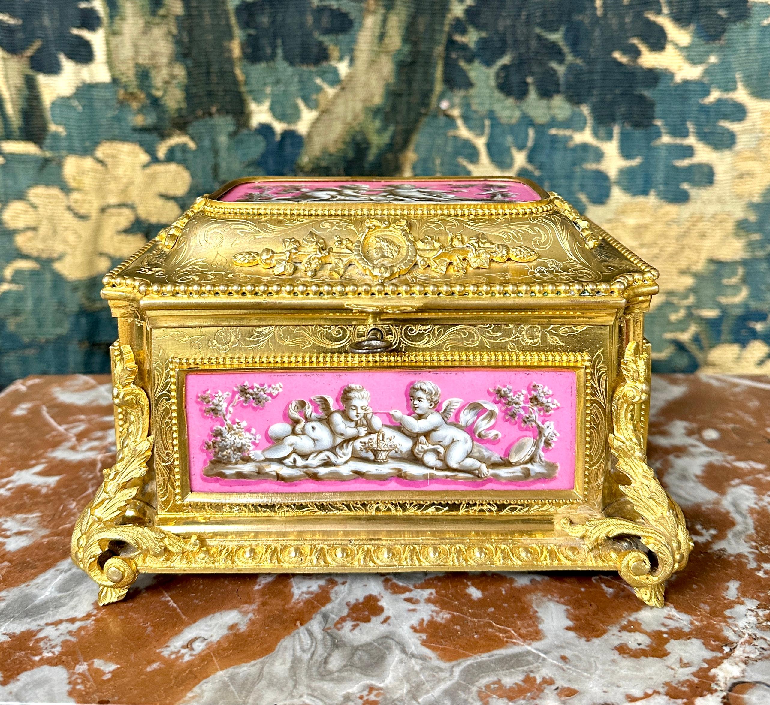 Box in gilded and chiseled bronze, and pink and white porcelain decorated with cherubs. Napoleon III work signed on the lock by Tahan, boulevard des Italiens at number 11. Famous cabinetmaker and table maker who had shops selling furniture and