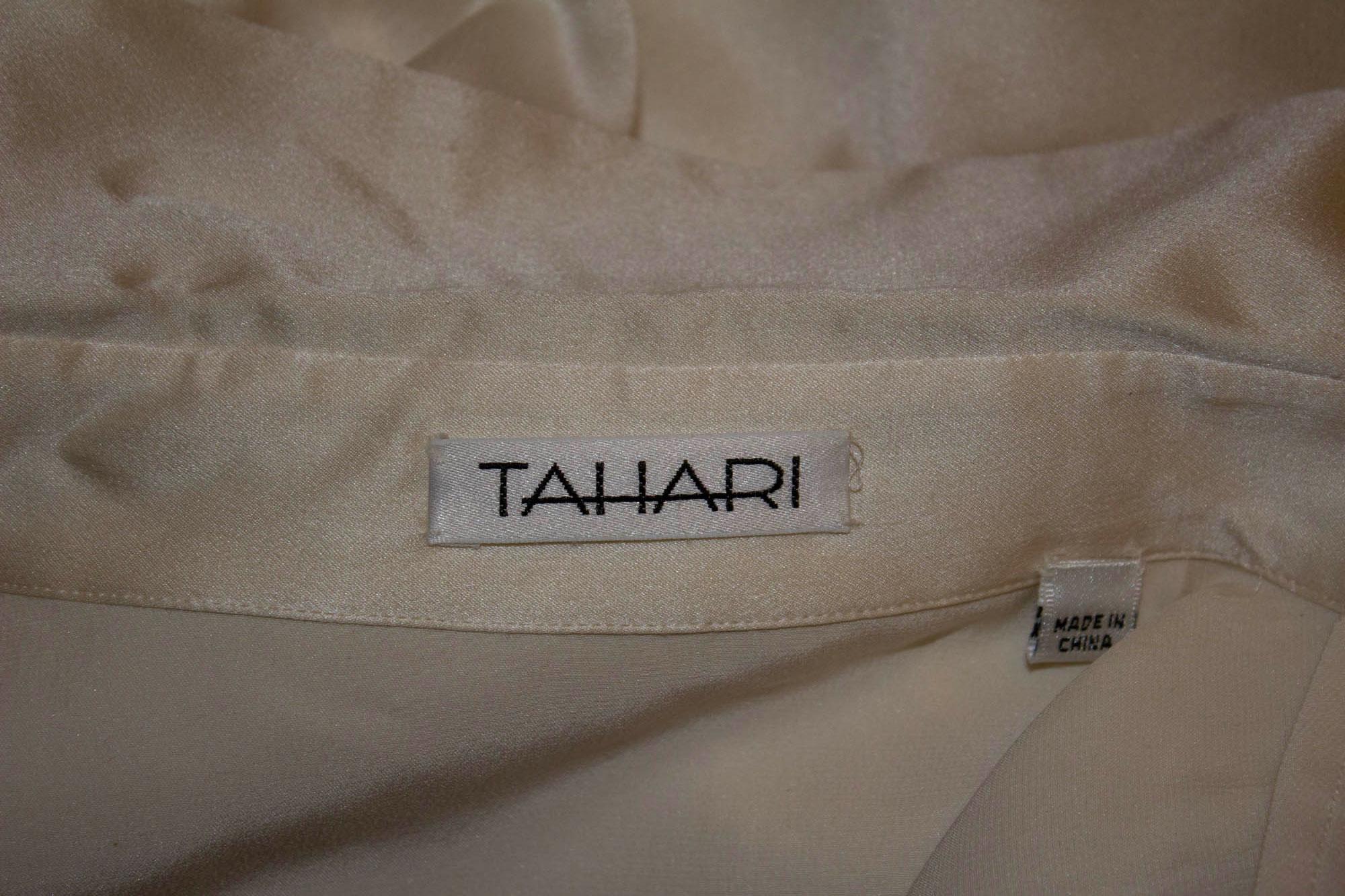 A chic shirt by Elie Tahari. The body of the shirt is in an ivory silk /satin, and the tail is sheer. It has turn back double cuffs and a button front. Size 12, Measurements: Bust up to 40'', length 31''