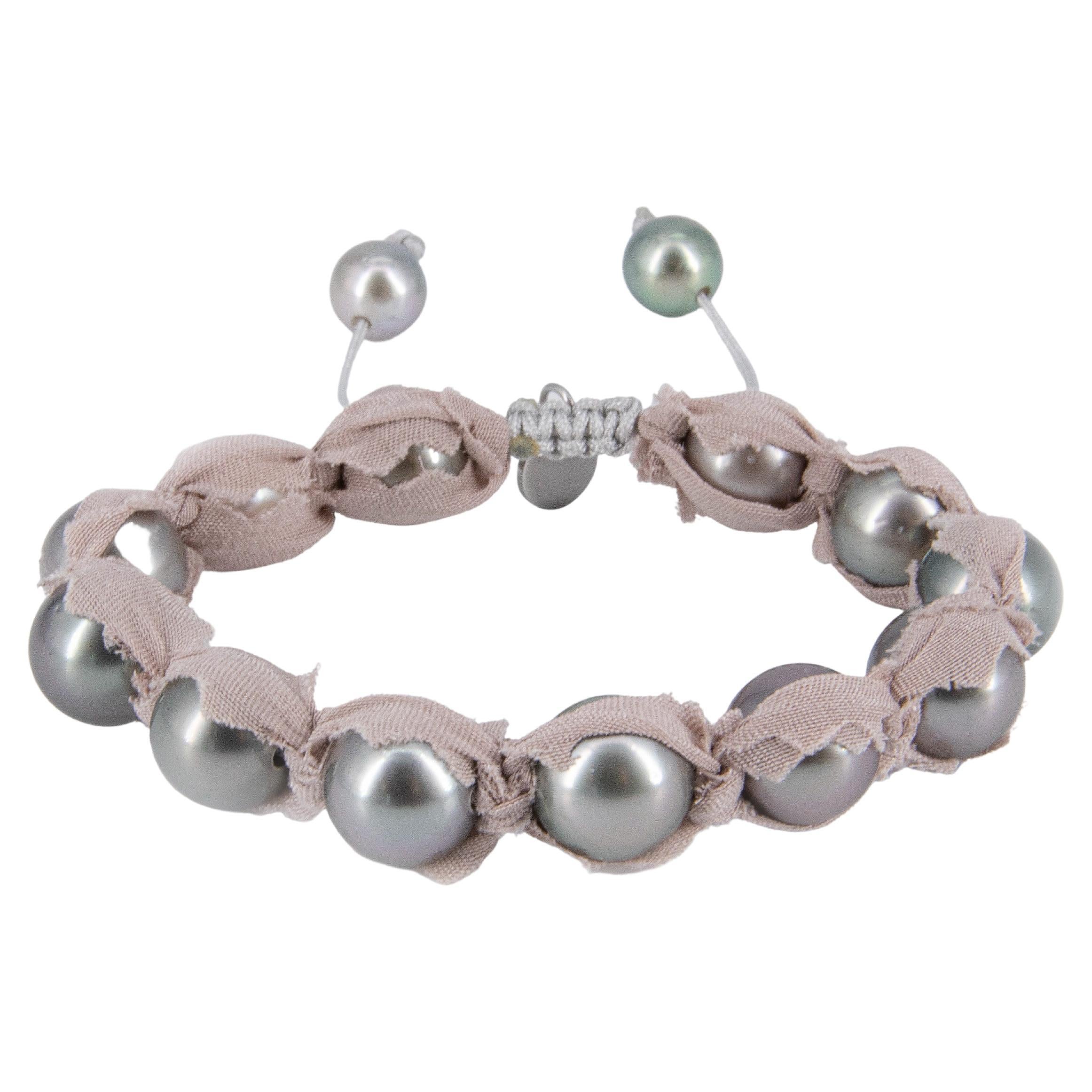 This bracelet is made of gray Tahitian pearls with 2 diamond pavé cones in blackened sterling silver plus 3 large rosé/purple iridescent baroque freshwater pearls. It is beaded on black cotton coated high quality elastic band, which lets the