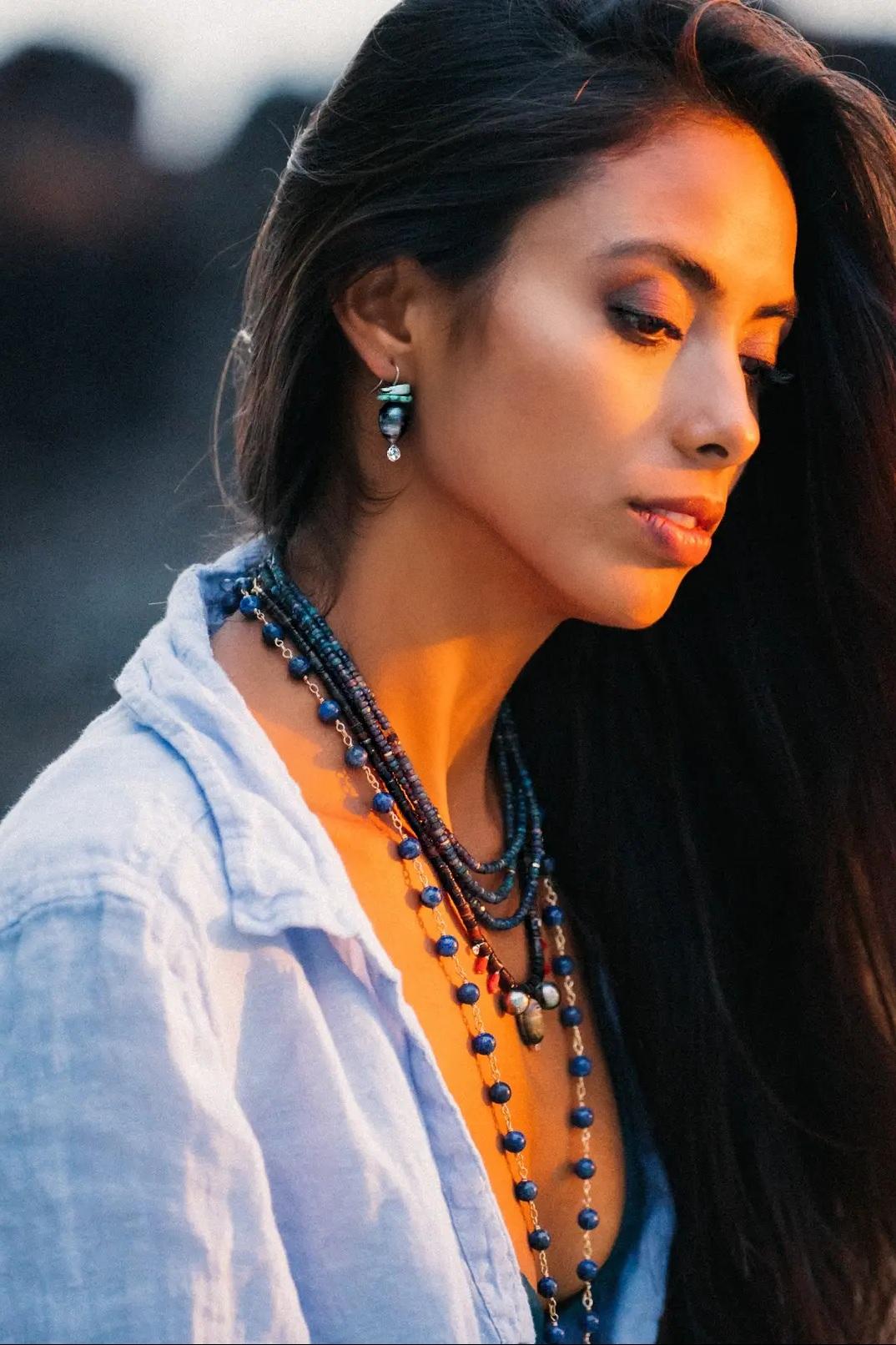 Apposing direction drop shaped Tahitian Pearls, approximately 11mm x 12.5mm, are adorned with mint colored matrix Natural Turquoise slivers. Rhodium plated Sterling Silver wire hooks with Cubic Zirconia bezel set accents at the bottom to finish this