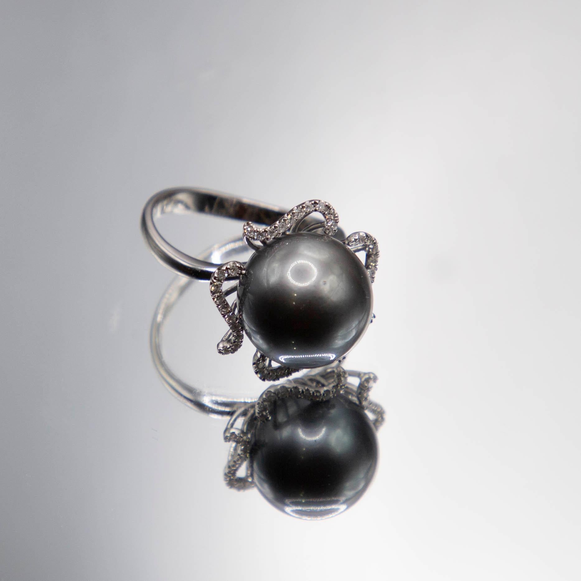 Der zentrale Edelstein in diesem eleganten Ring ist eine seltene 12,5 mm große Tahiti-Perle, die eine satte schwarz-graue Farbe und einen sehr hohen Glanz aufweist,  eine praktisch makellose Oberfläche, eine gleichmäßige Sättigung, eine