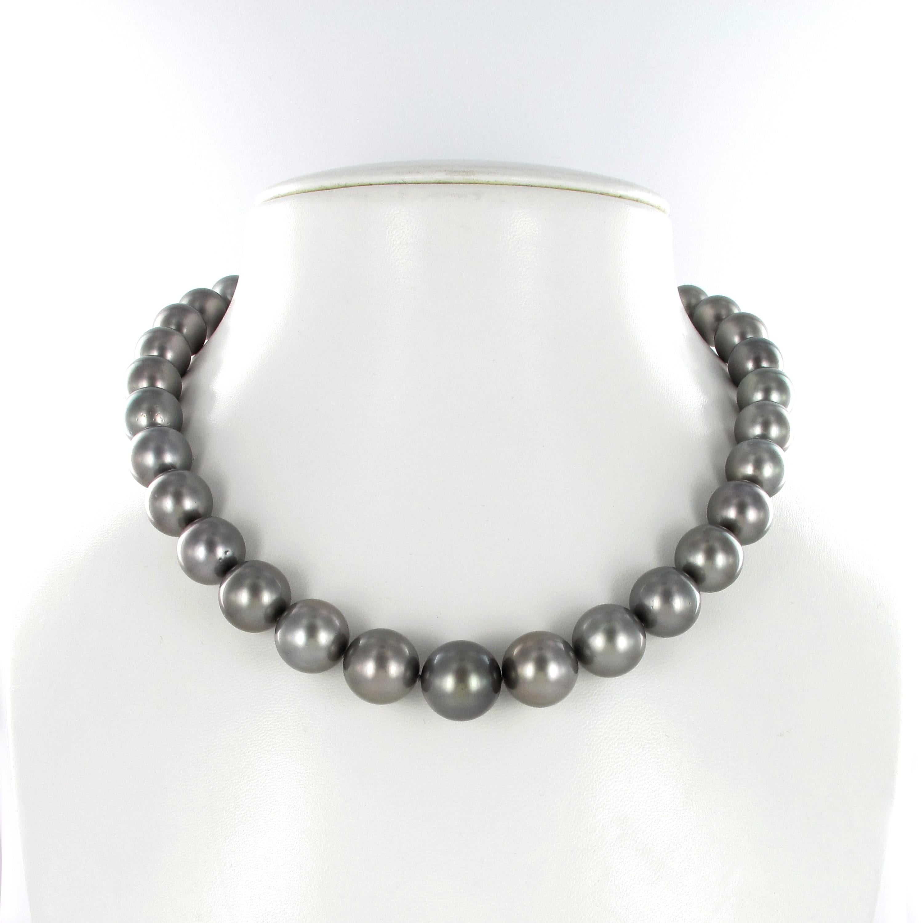 This strand consists of 33 round dark gray Tahitian cultured pearls graduating from 12.0 mm to 15.1 mm. The pearls are of round shapes, with a slightly spotted surface and a good luster. The ball clasp in 18 karat white and yellow gold is set with 6