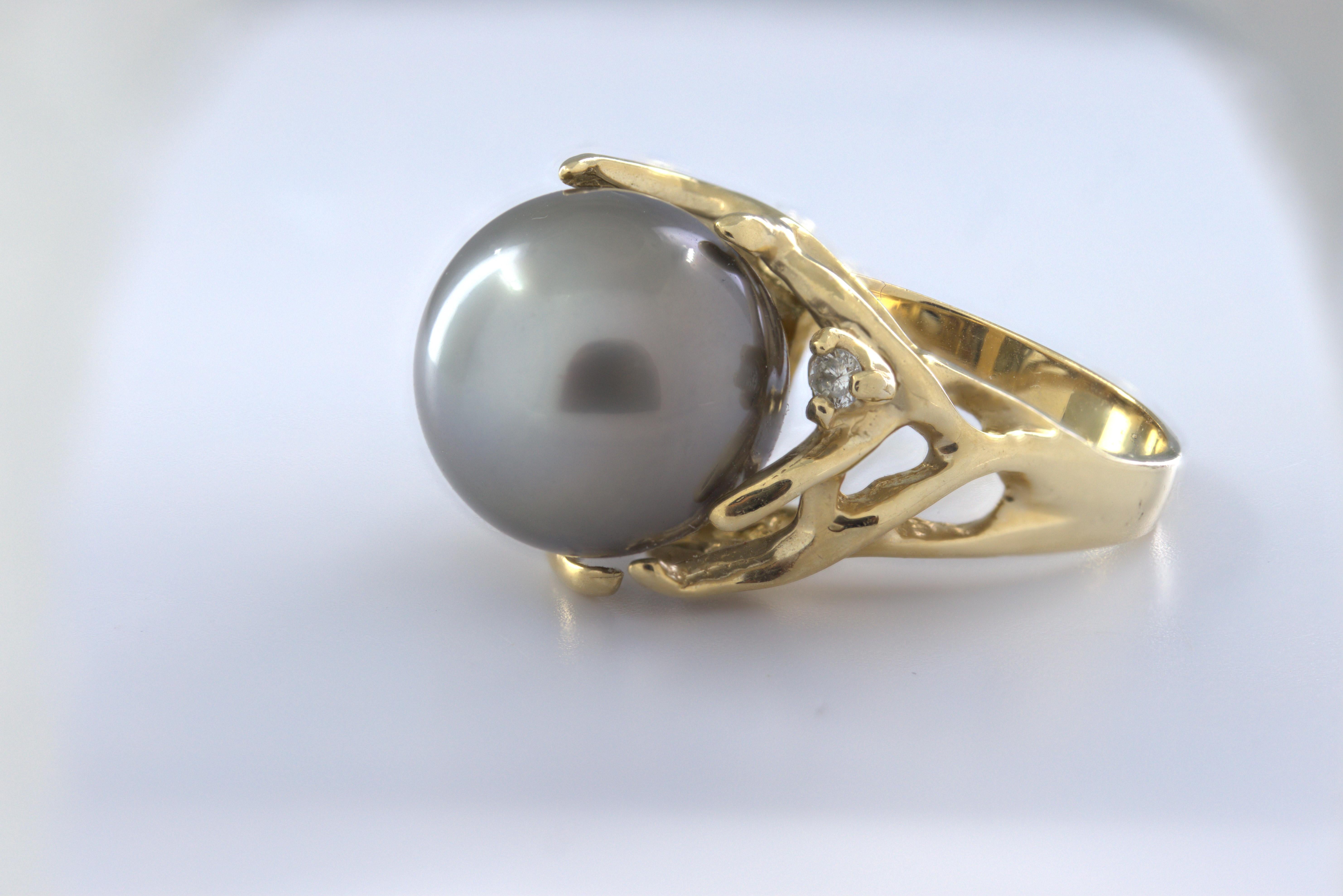 Featuring (1) 12.7 mm gray Tahitian cultured pearl, accented by (1) full-cut diamond, 0.03 ct., I, J, set in an asymmetric, 14k yellow gold tendril form mounting, 14.6 mm tapering to 2.8 mm, size 8, Gross weight 8.58 grams.