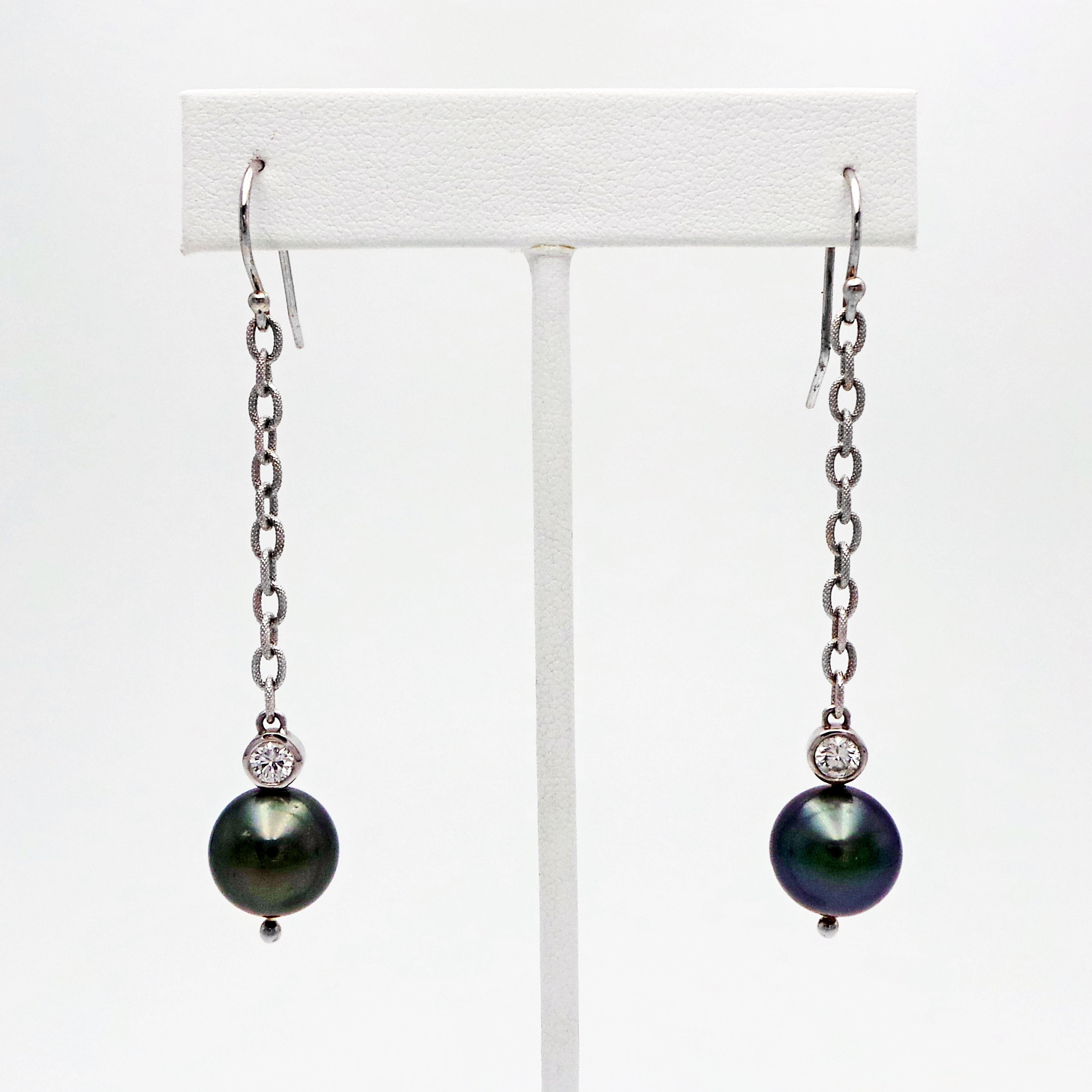 Tahitian Pearl, Diamond, and 14k white gold dangle drop earrings are a contemporary yet timeless style. Round Tahitian Pearls (13mm) and bezel set Diamonds (0.60 total carat weight, SI1 clarity, G-H color) are suspended from solid 14k white gold