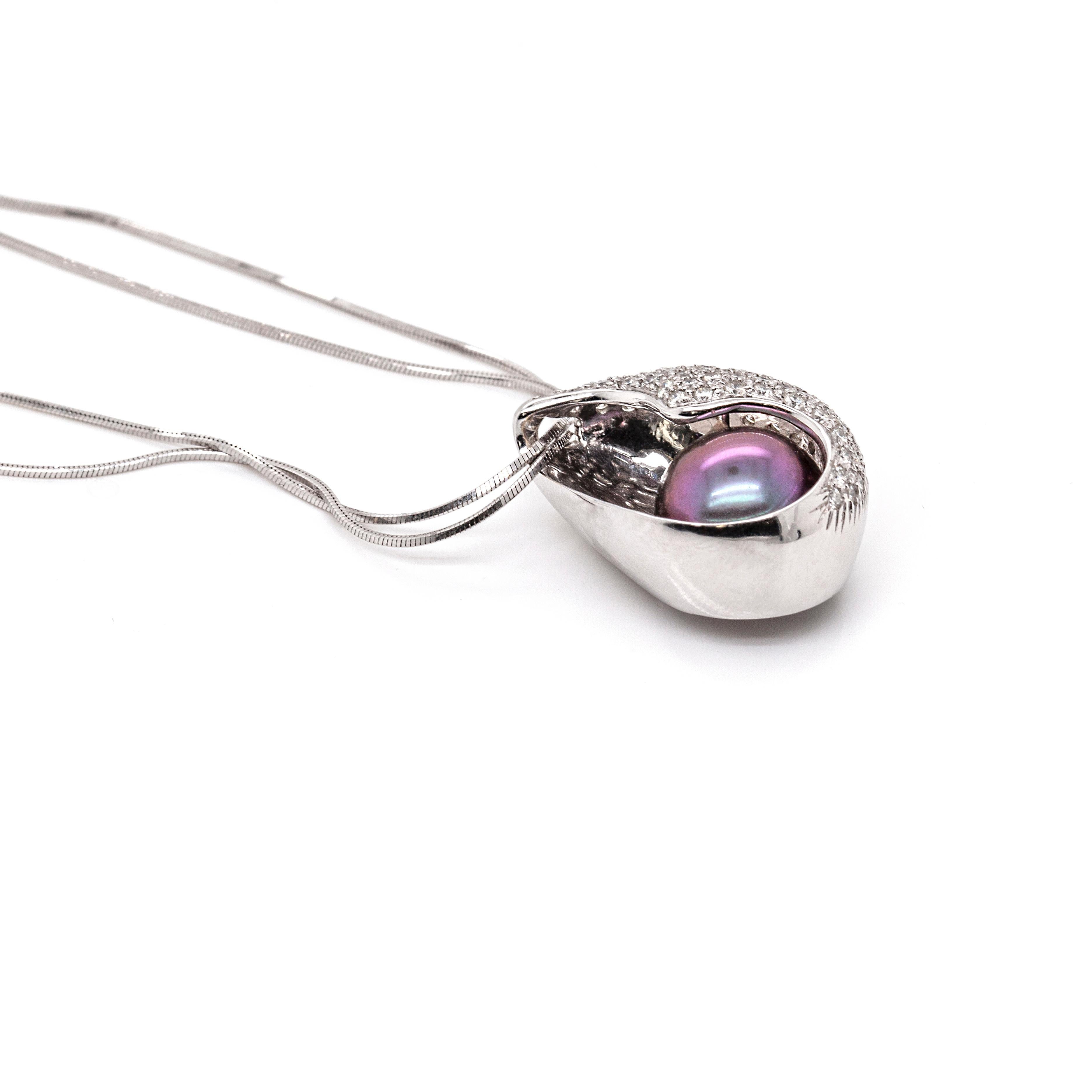 This is a striking Italian-made 18ct white gold necklace, featuring a gorgeous black pearl cradled in a pavé set conch shaped pendant. The pendant boasts approximately 0.65 carats of round brilliant cut diamonds. The back of the pendant is left