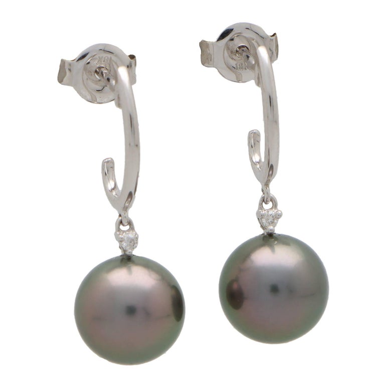 A beautiful pair of Tahitian pearl and diamond drop earrings set in 18k white gold.

Each earring is firstly composed of a half white gold hoop which is secured to reverse with a post and butterfly fitting. Hanging from the hoop is an articulated
