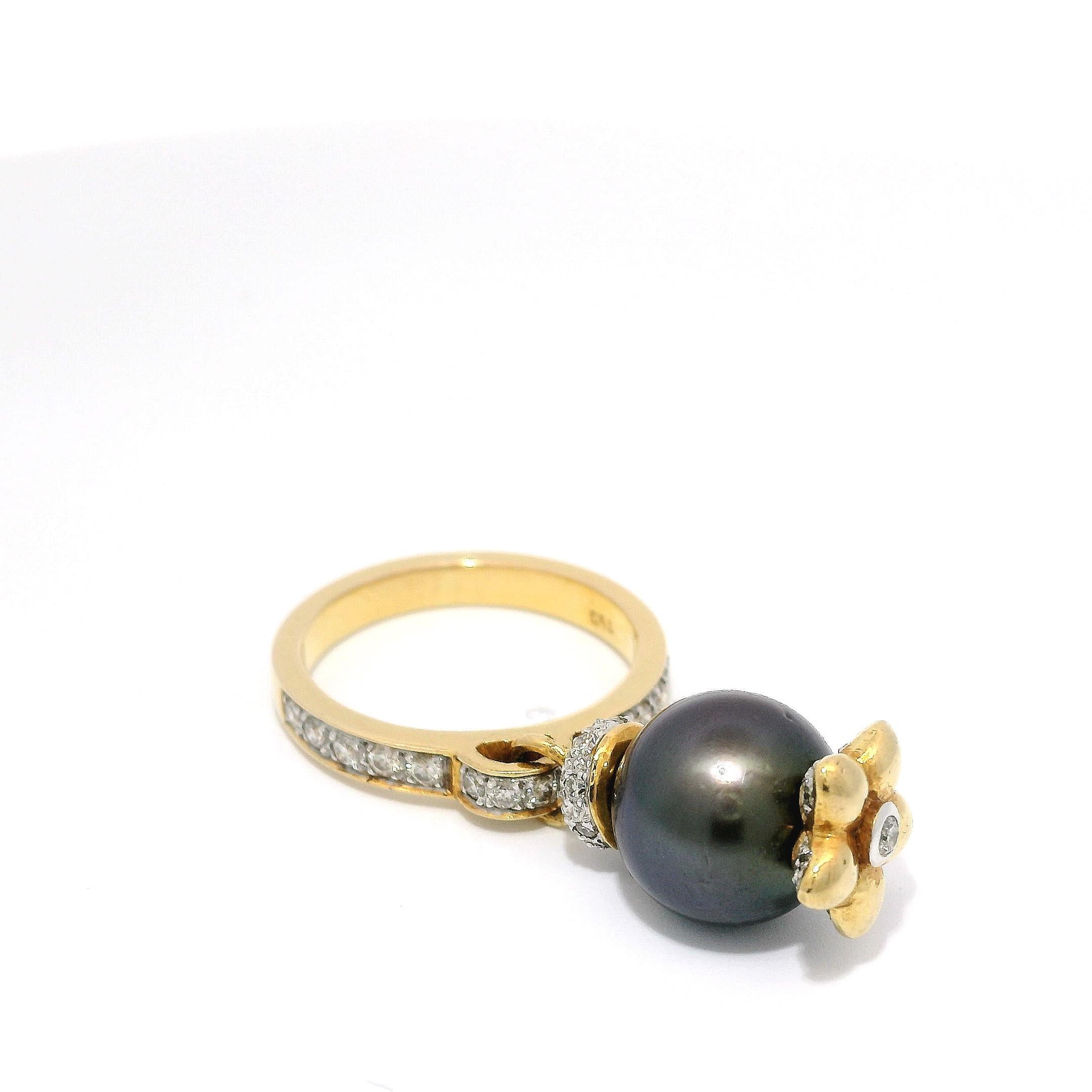 Cette bague d'une élégance intemporelle est ornée d'une perle noire lustrée de Tahiti, gracieusement suspendue à un anneau en or 18 carats incrusté de diamants étincelants. Le design unique de cette pièce exquise évoque la beauté de la