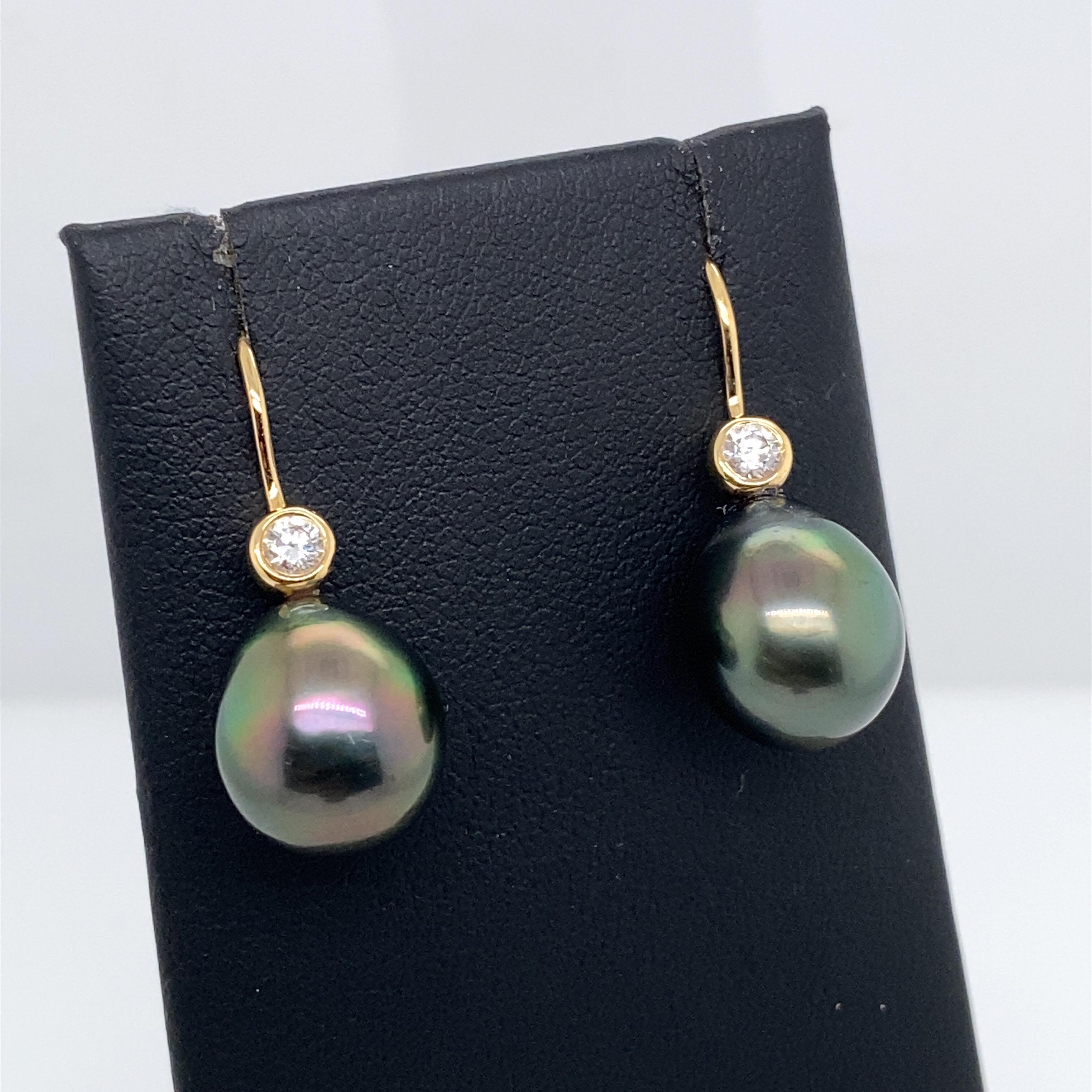 18K Yellow gold drop earrings featuring two Tahitian pearls measuring 11-12 mm with bezel set round brilliants weighing 0.20 carats. 
Color G-H
Clarity SI