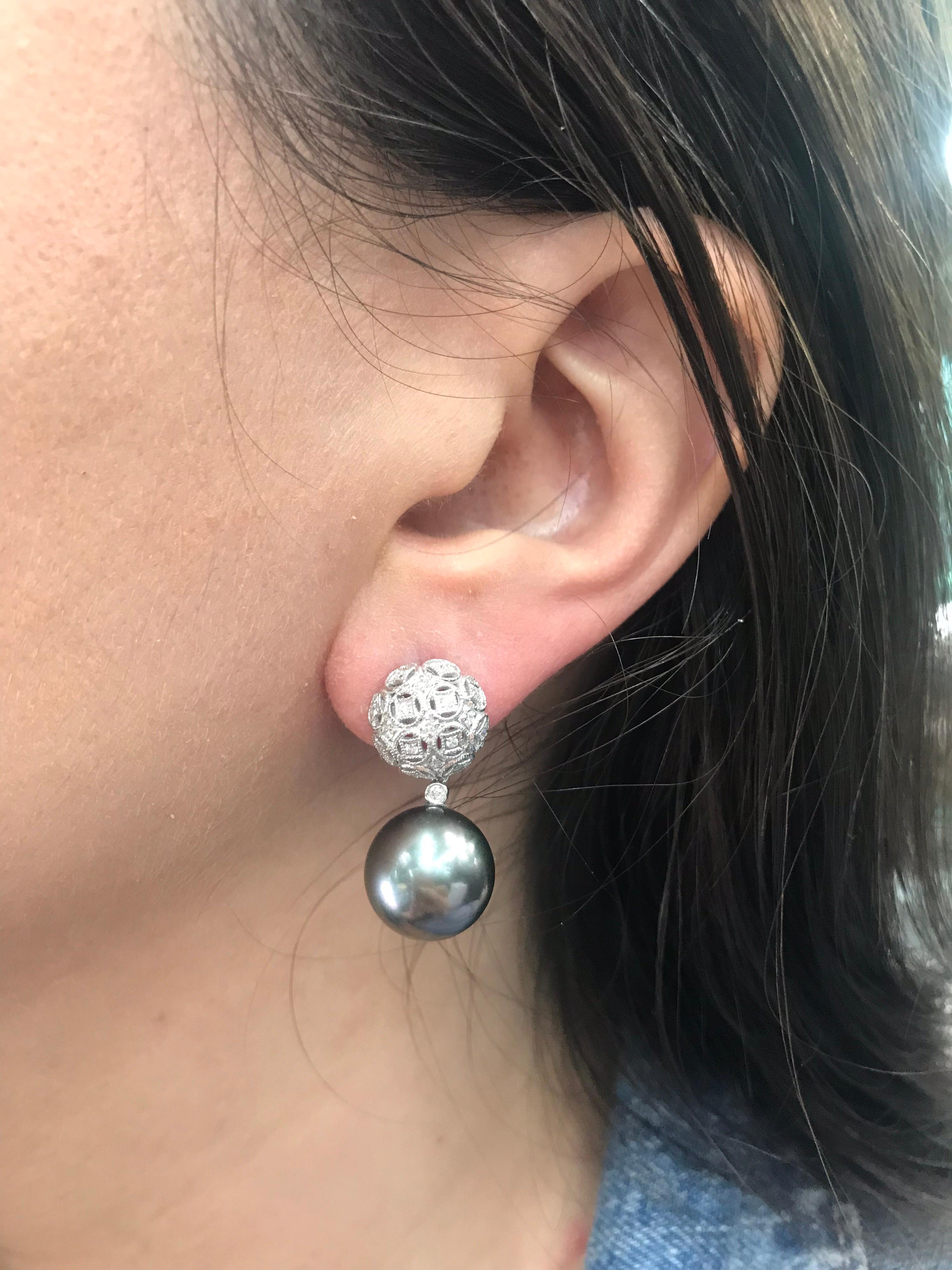 18K White gold drop earrings featuring two Tahitian pearls measuring 13-14 mm and round brilliants weighing 0.30 carats. 