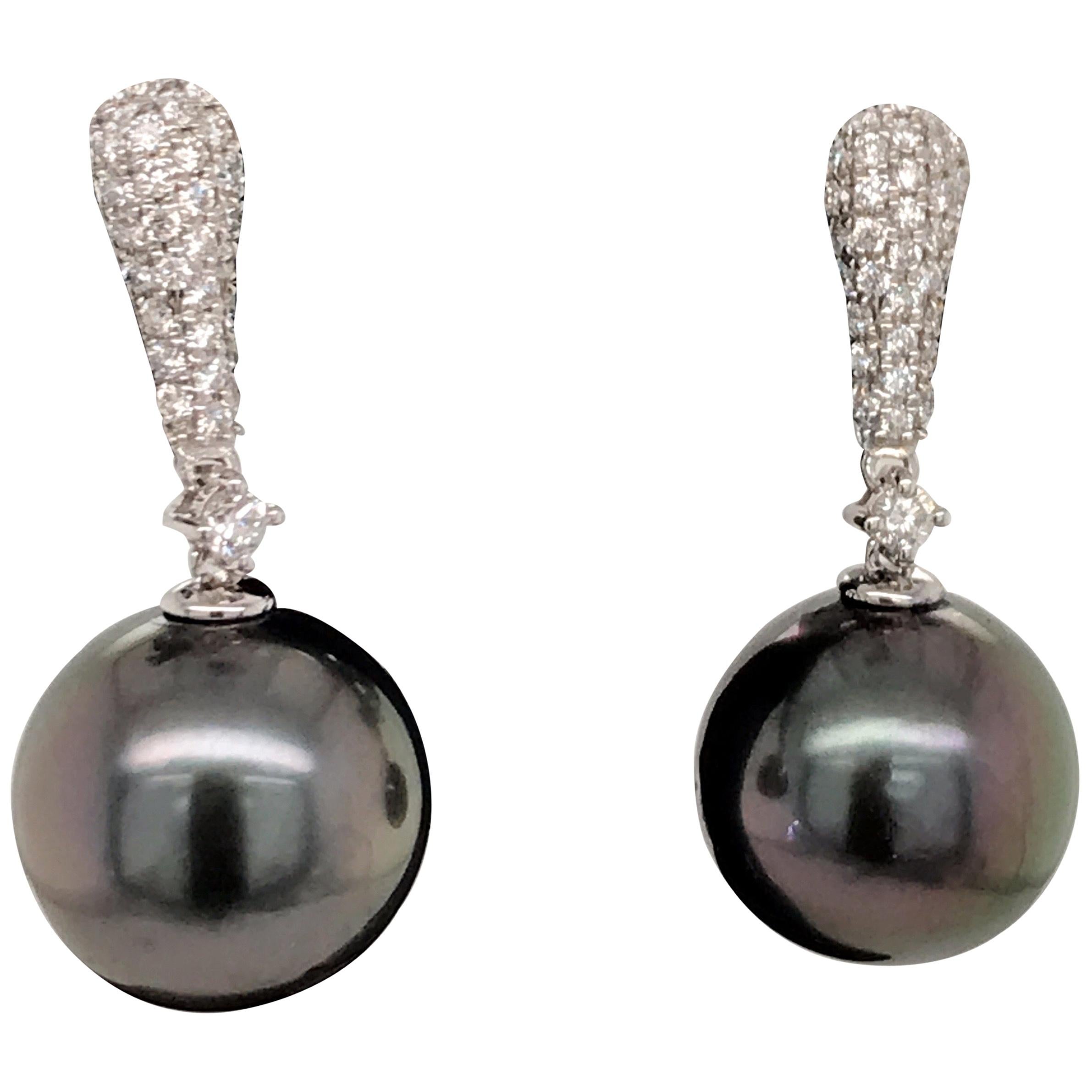 18K White gold drop earrings featuring two Tahitian pearls measuring 11-12 MM flanked with 68 round brilliants weighing 0.37 carats.
Color G-H
Clarity SI