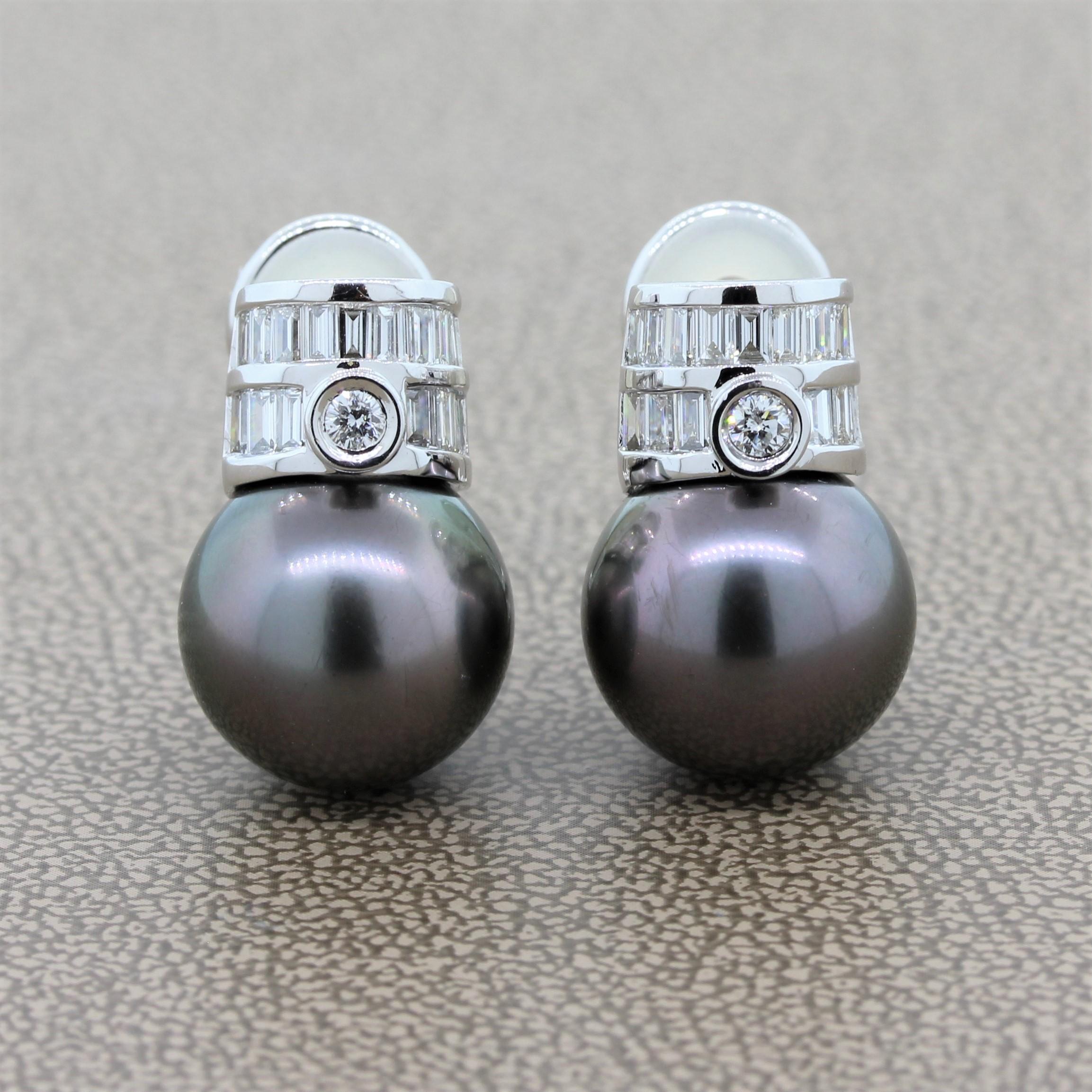 An elegant pair of earrings featuring perfectly round and matching 13mm Tahitian pearls in an 18K white gold setting. The pearls are topped with two rows of channel set baguette cut diamonds with a bezel set round cut diamond in the center totaling